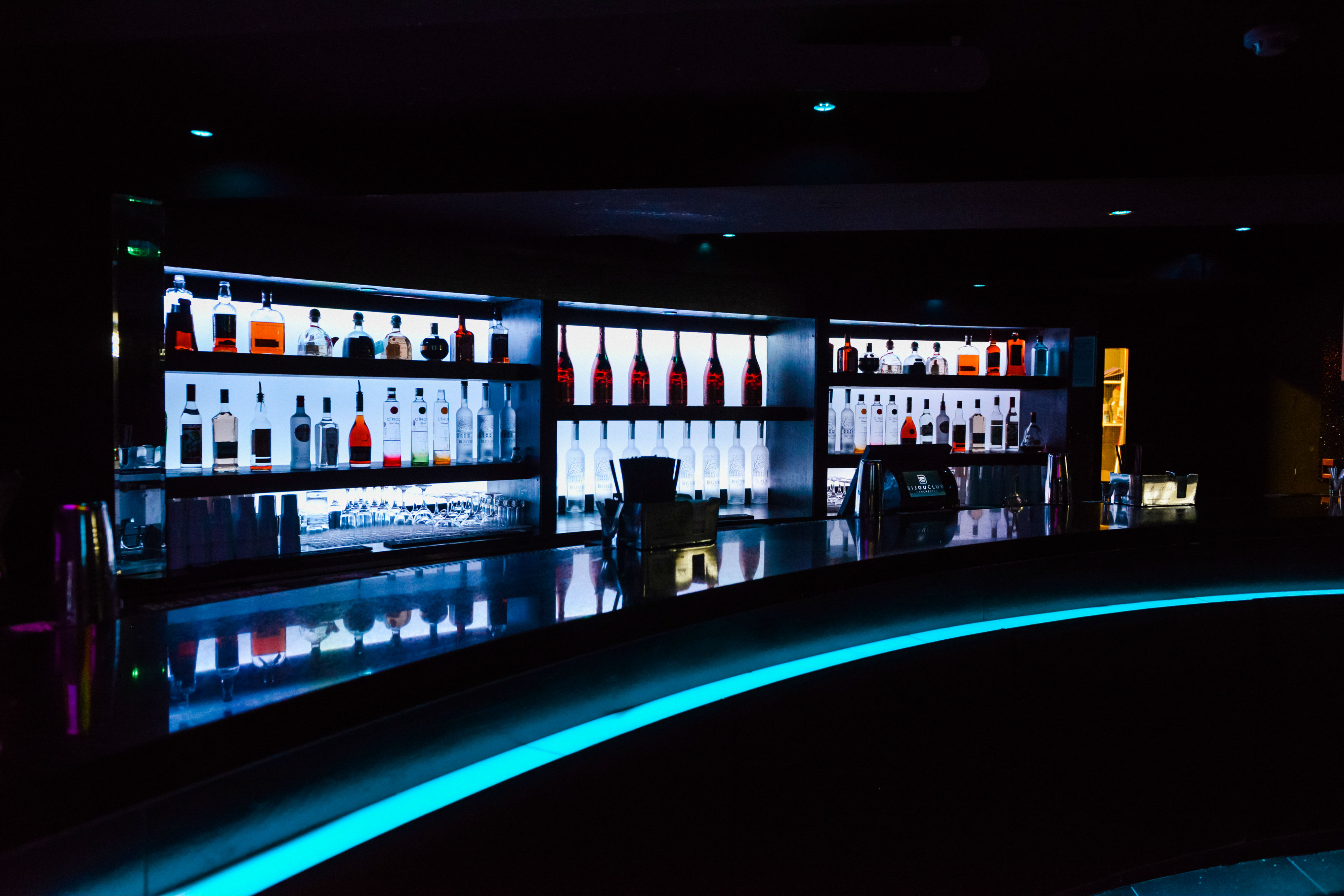 Sleek cocktail bar at Bijou Club with illuminated shelves for social gatherings.