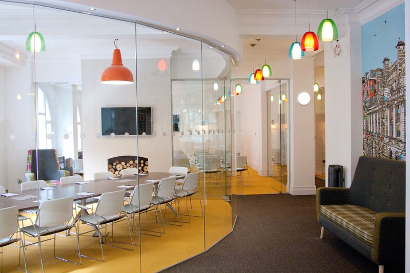 Modern meeting room with glass walls, vibrant lighting for collaboration and brainstorming.