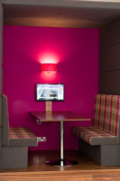 Cozy business lounge with vibrant pink wall for informal meetings and brainstorming sessions.