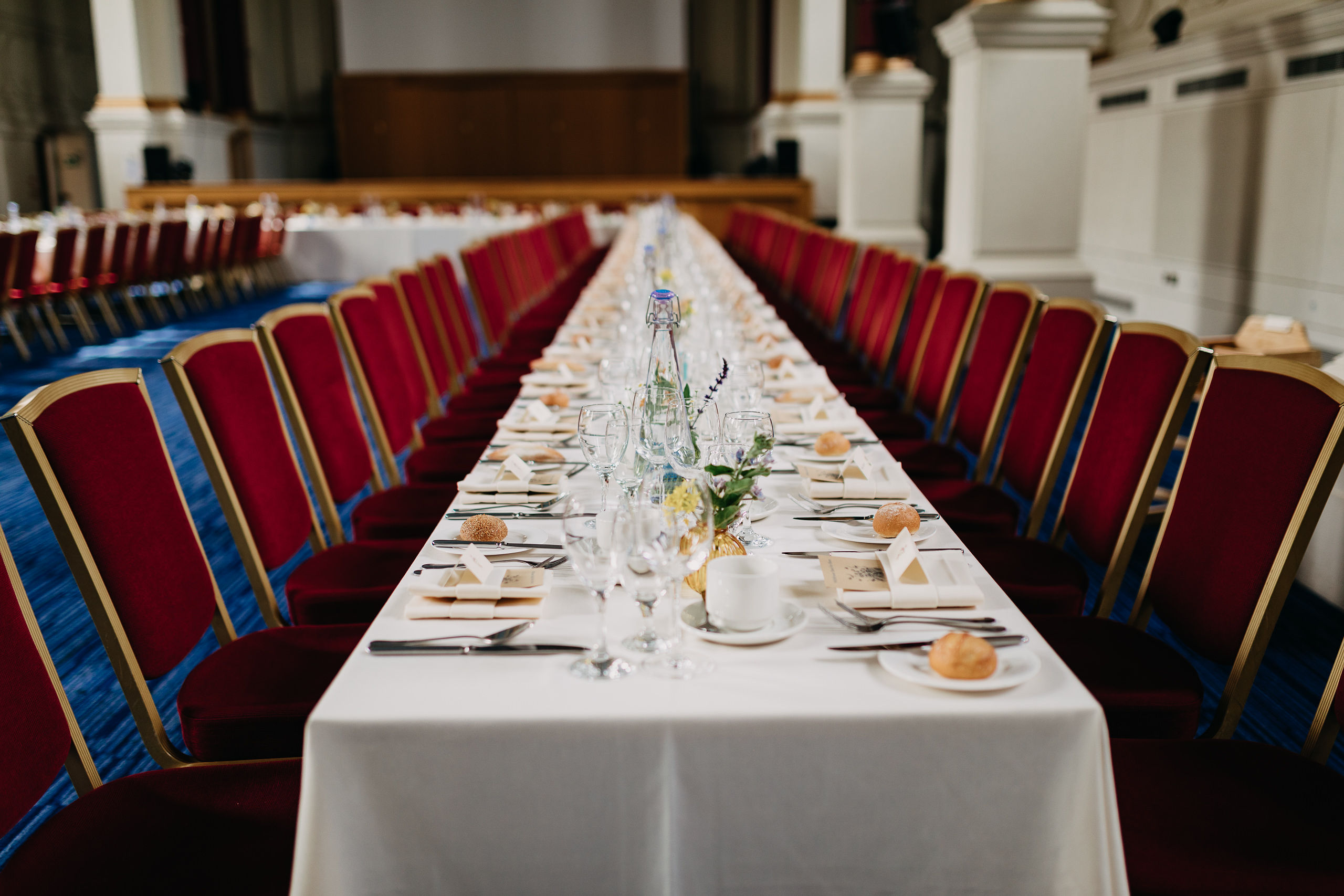 Great Hall banquet setup with white linens, red chairs for formal events and celebrations.