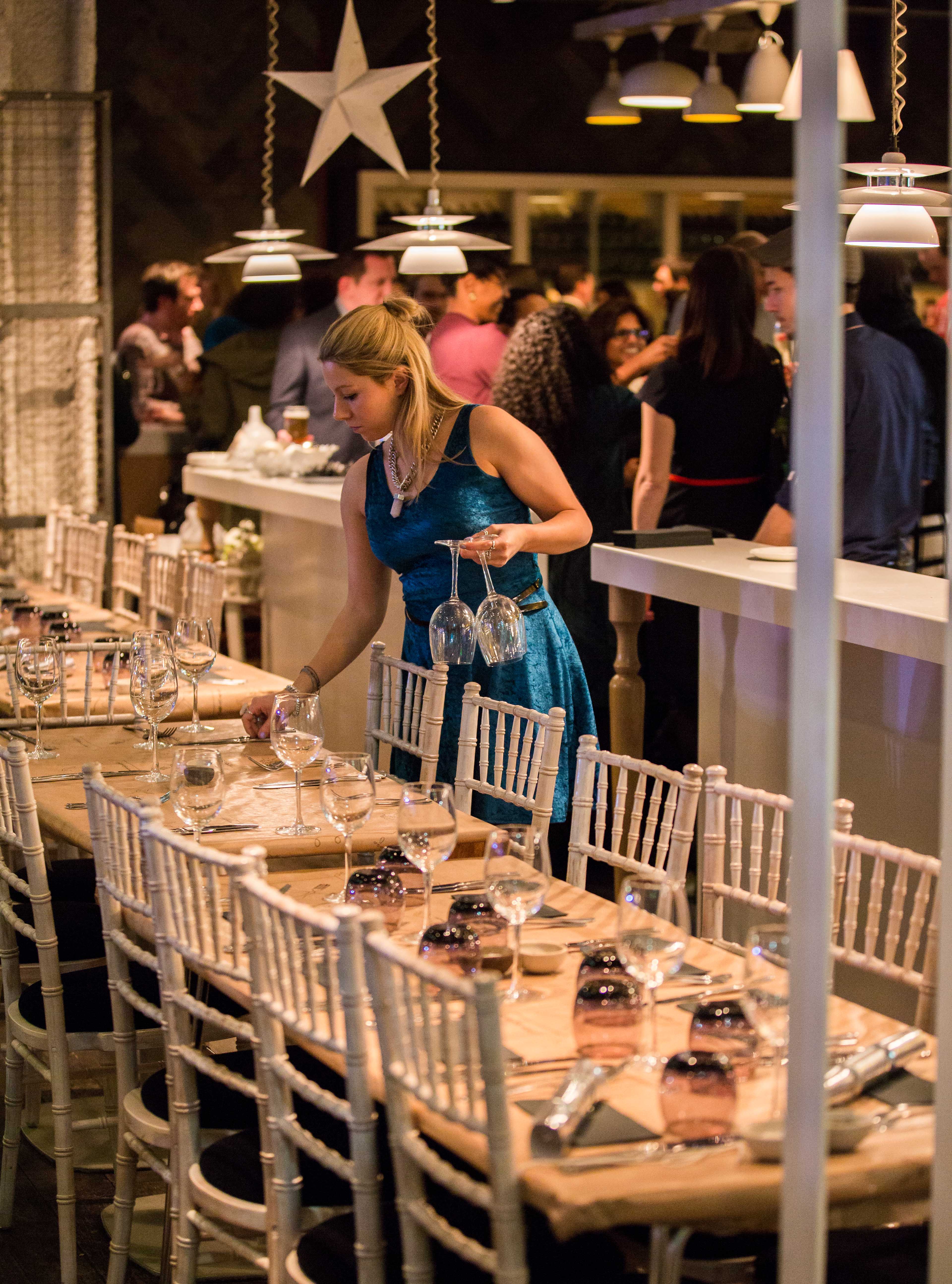 Vibrant event space in The Parlour with guests mingling and elegant glassware setup.