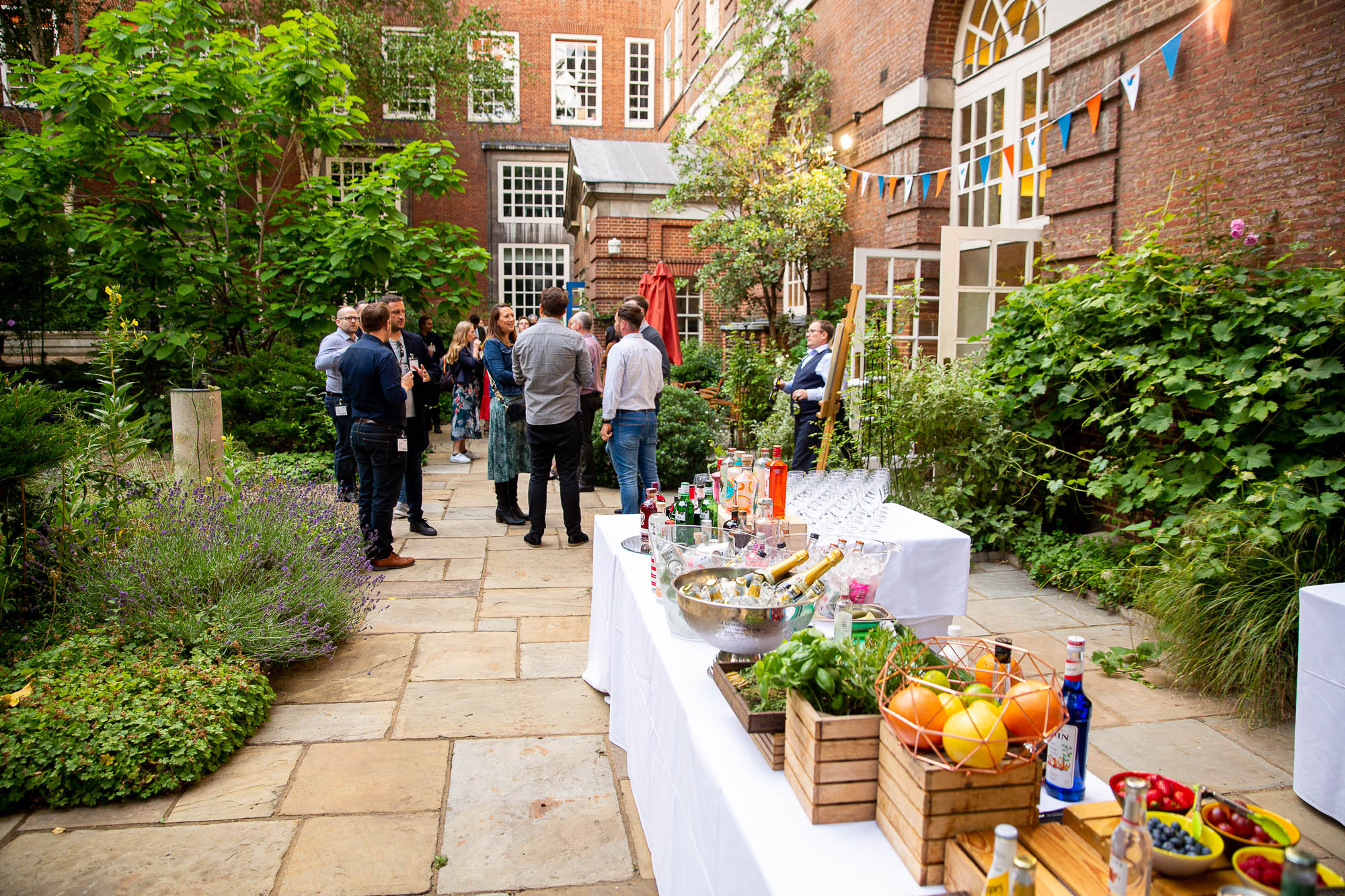 Vibrant garden event setup with tables, refreshments, and guests at BMA House.