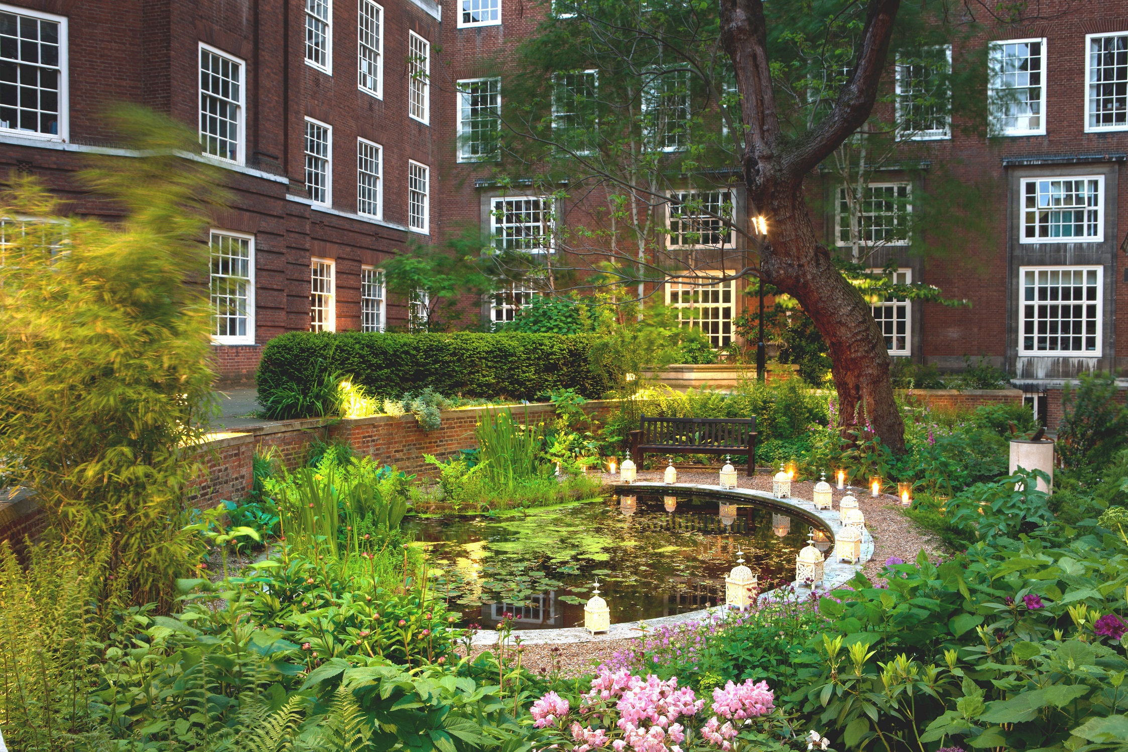 Serene outdoor event space with lush greenery and tranquil pond at BMA House.