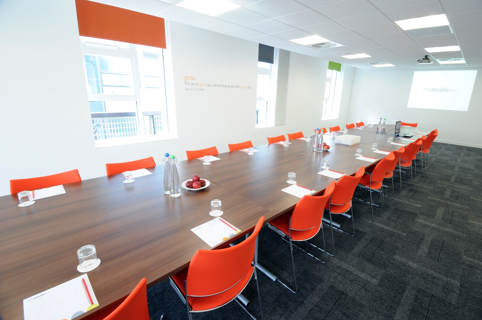 Modern conference room in Manchester with wooden table and orange chairs for corporate meetings.