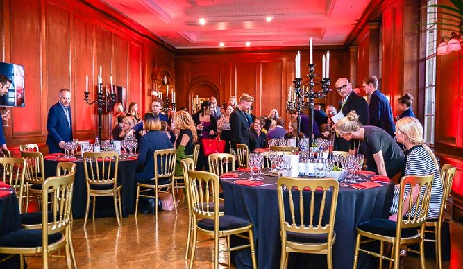 Formal reception, warm red light, elegant gold chairs, networking event