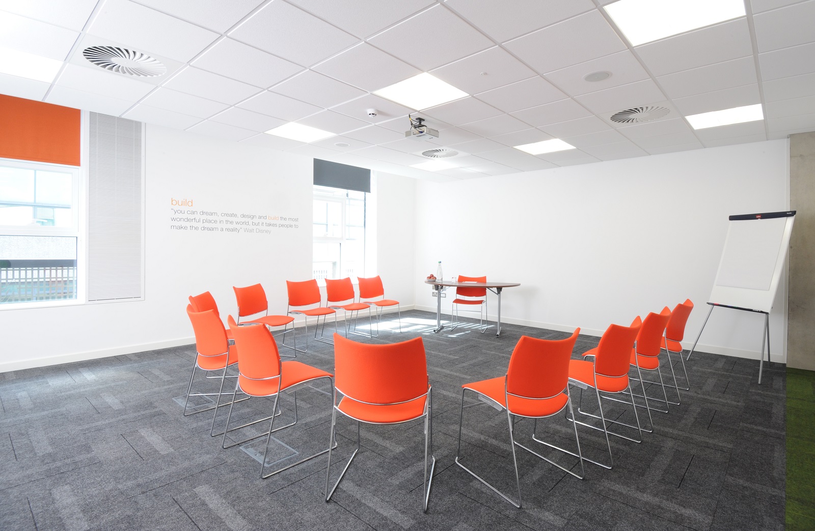 Modern meeting room in Manchester with orange chairs, ideal for workshops and brainstorming.