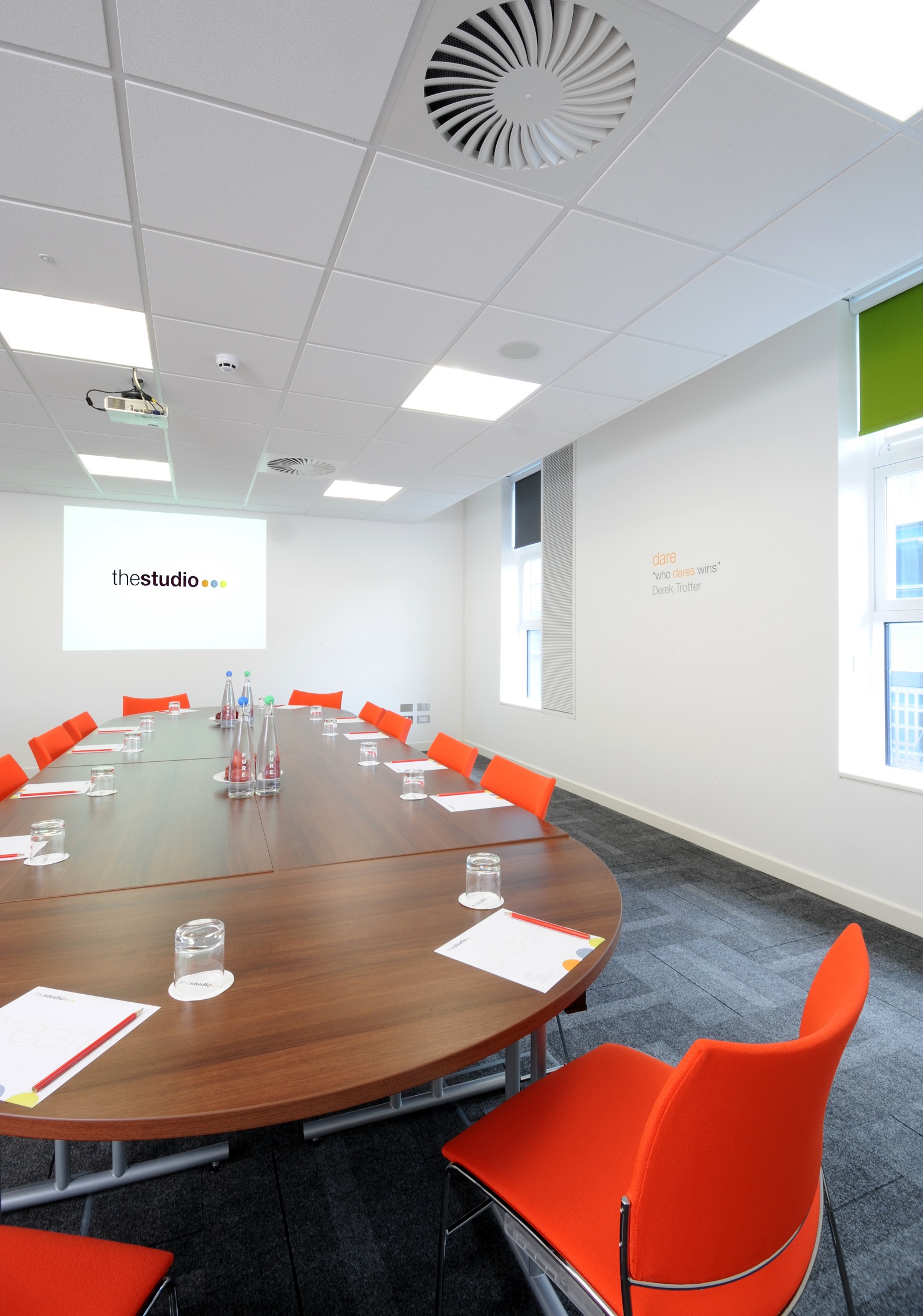 Modern meeting room in Manchester with wooden table and orange chairs for corporate workshops.