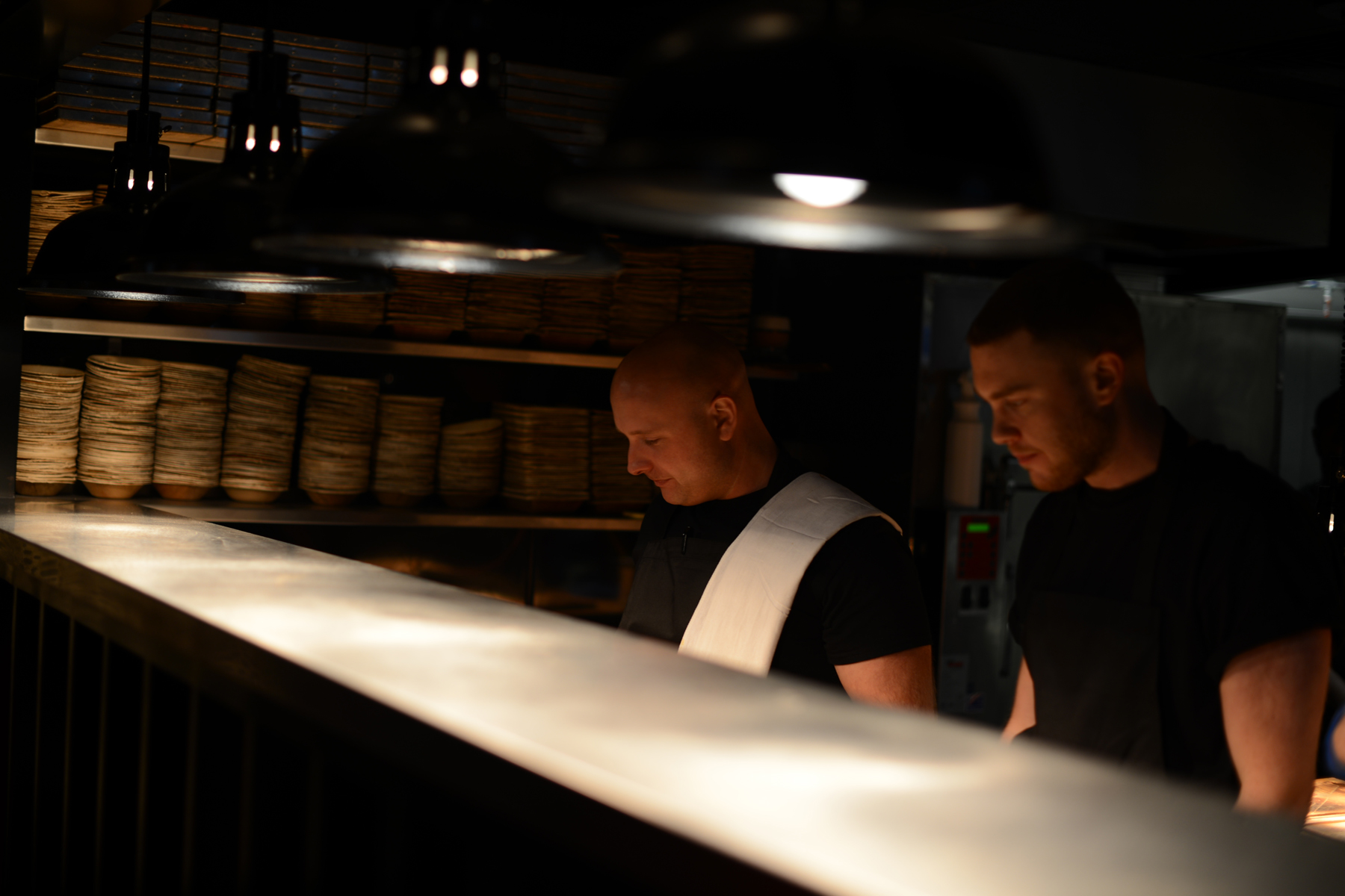 Culinary chefs in a dimly lit kitchen at HotBox London for upscale event catering.