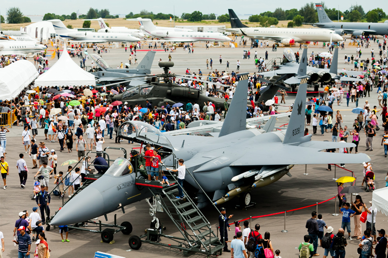 Outdoor airshow at Changi Exhibition Centre with military and private aircraft on display.