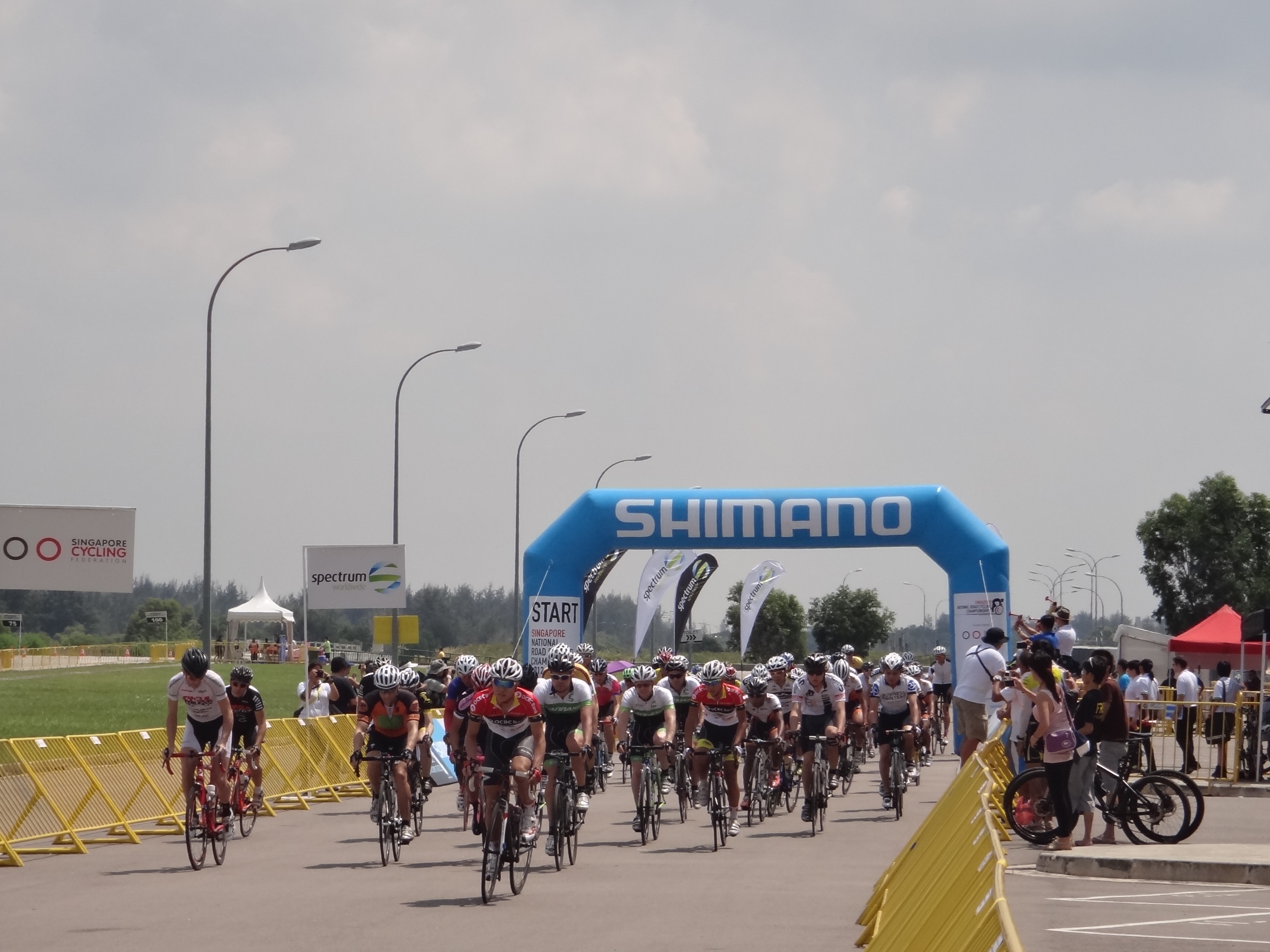 Vibrant cycling event at Changi Exhibition Centre with branded archway and sponsor signage.
