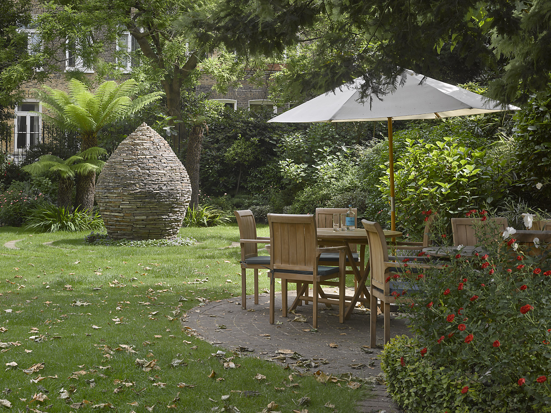 Serene garden meeting space at K+K Hotel George with stone sculpture, ideal for networking events.
