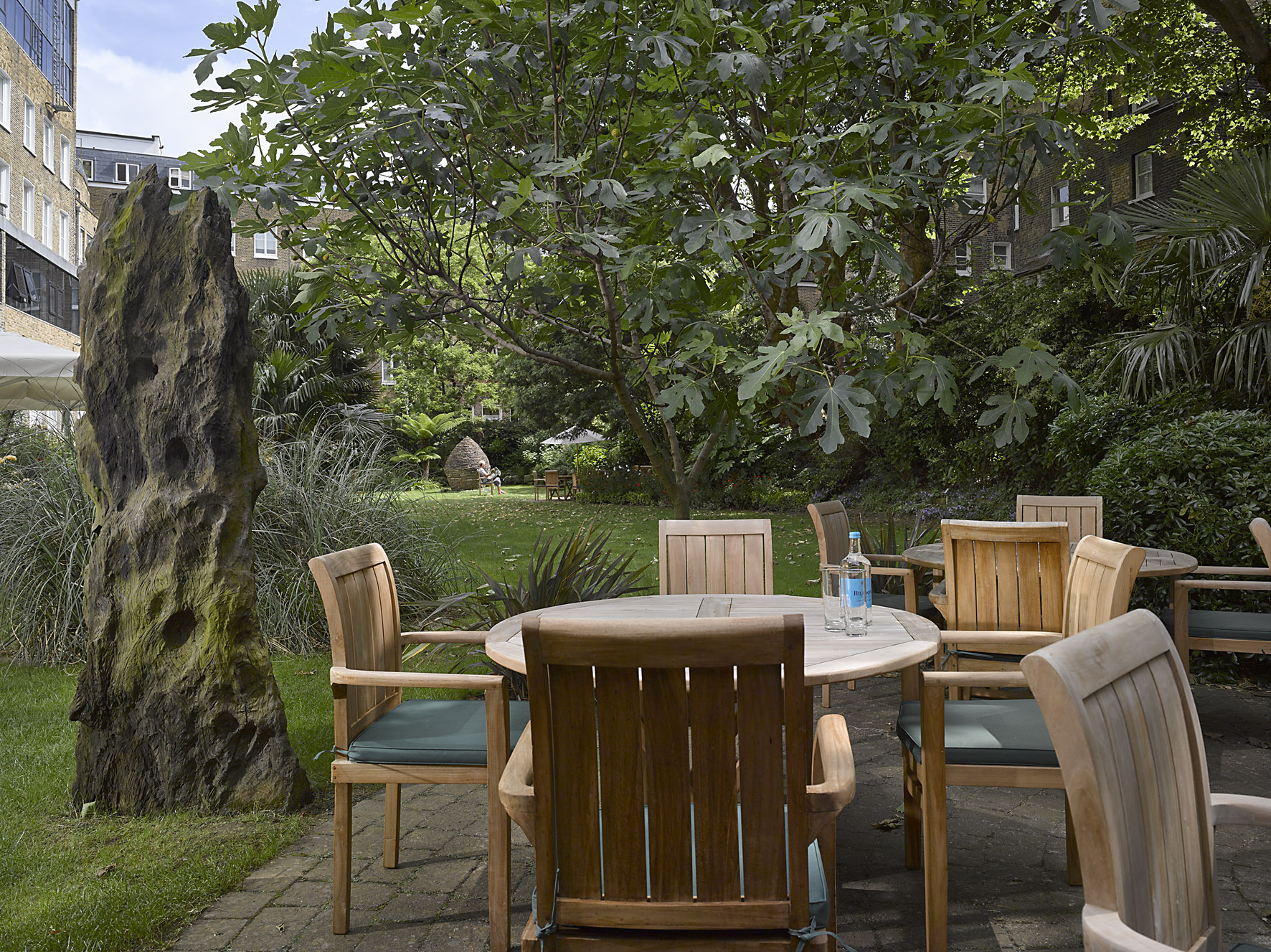 Serene garden meeting space with wooden table, ideal for corporate events and relaxation.