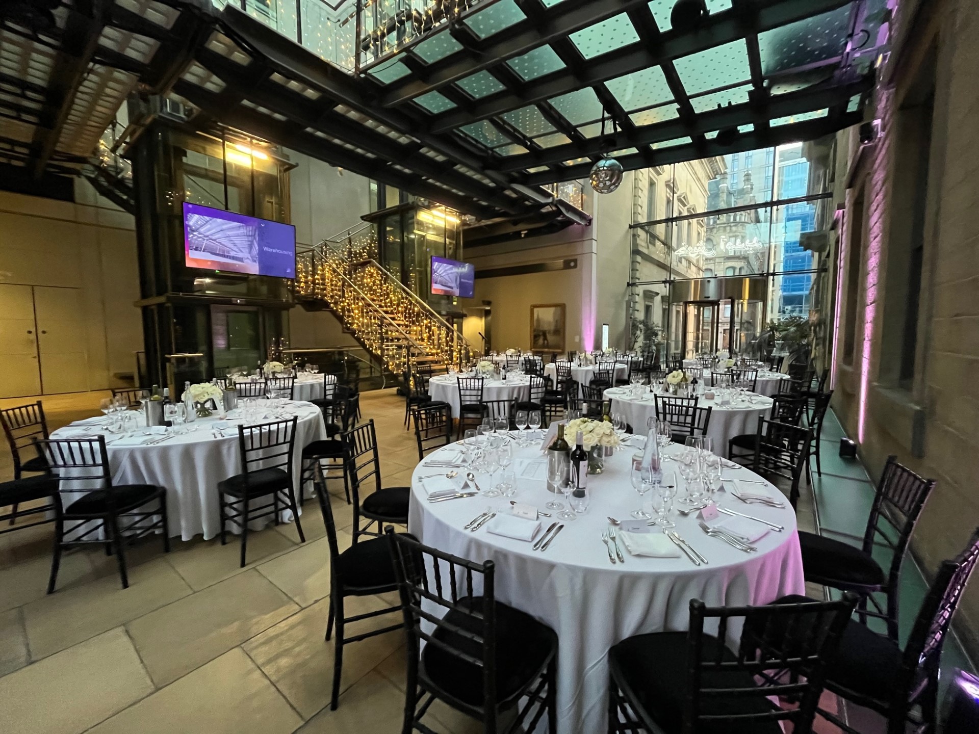 Atrium at Manchester Art Gallery: elegant event space with round tables for corporate gatherings.