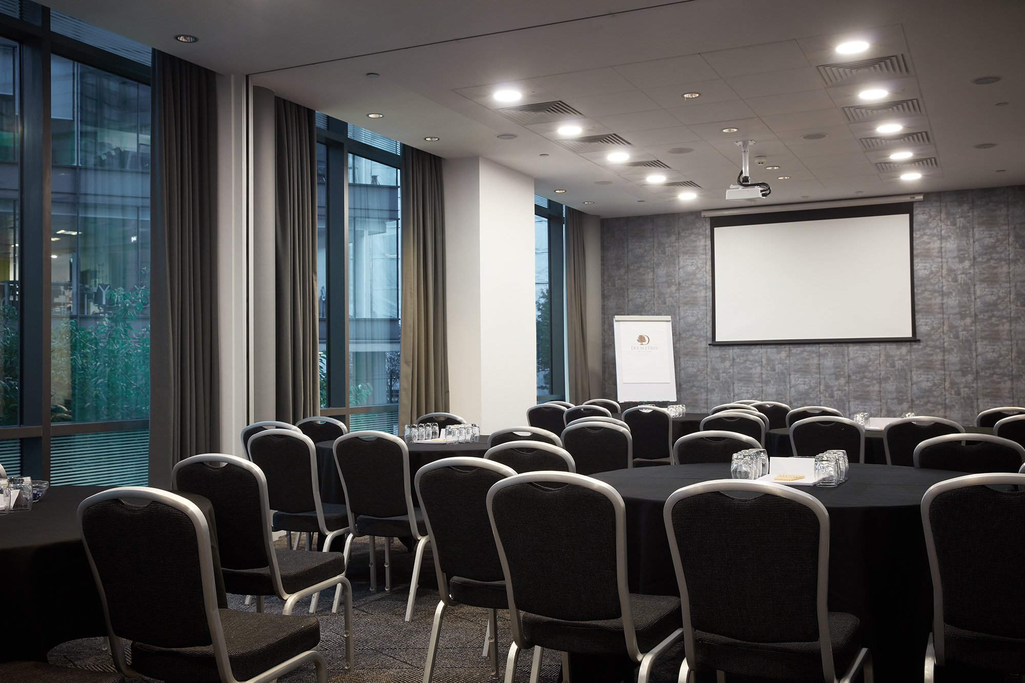 Meeting room at DoubleTree Manchester with round tables, ideal for workshops and presentations.