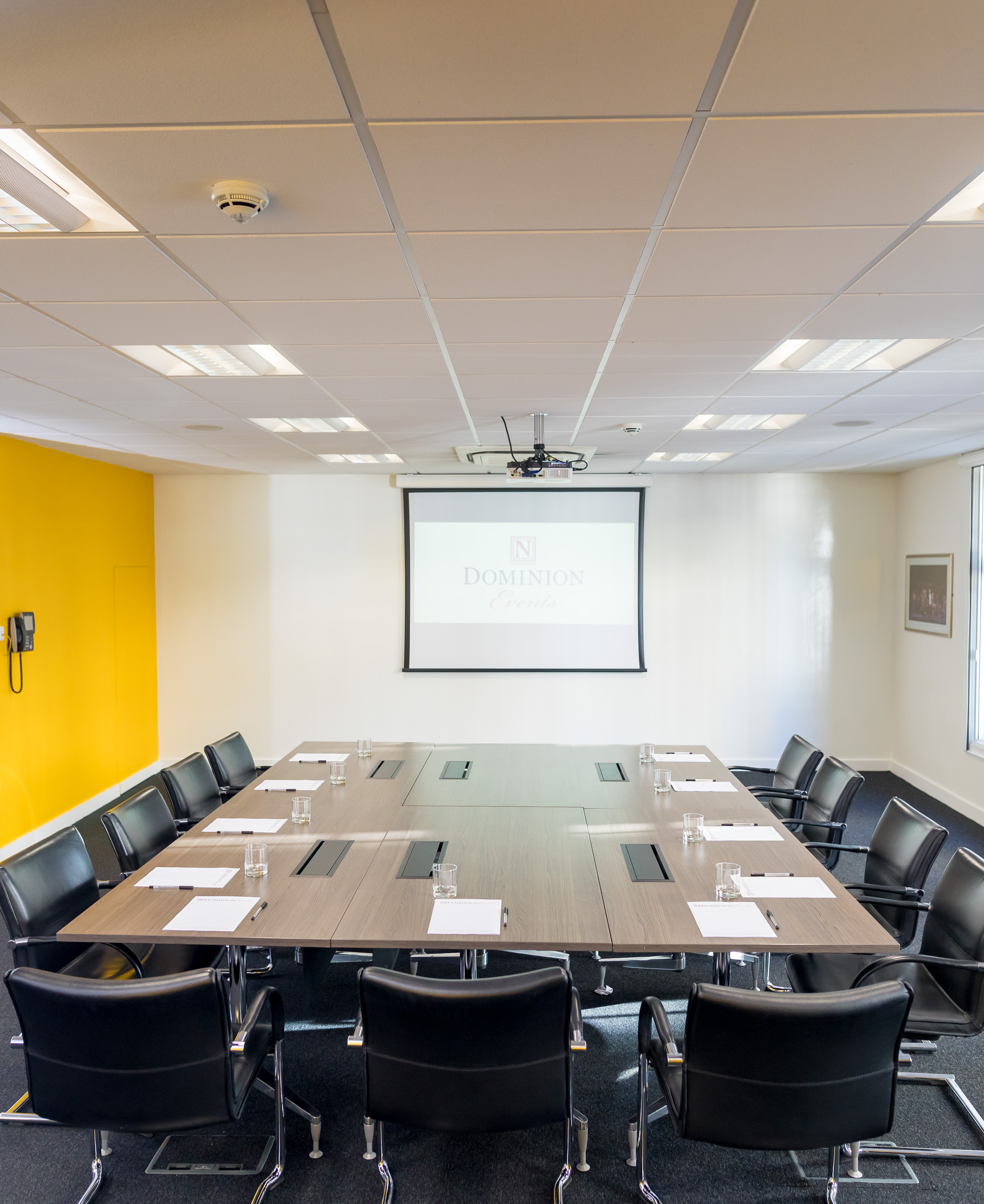 Boardroom at Dominion Theatre with projector screen, ideal for professional meetings and events.