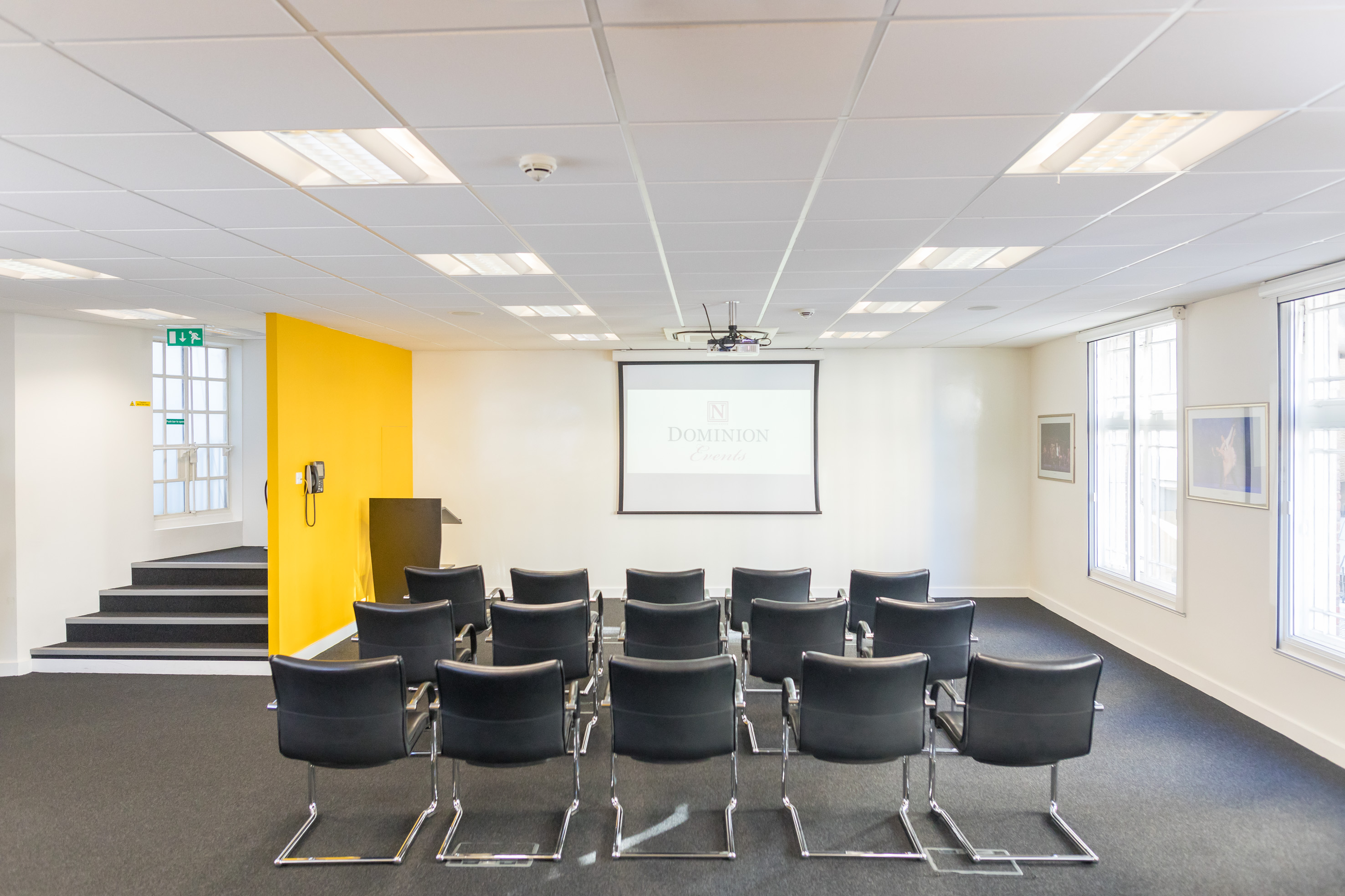 Modern meeting room in Dominion Theatre with projector screen, ideal for corporate events.