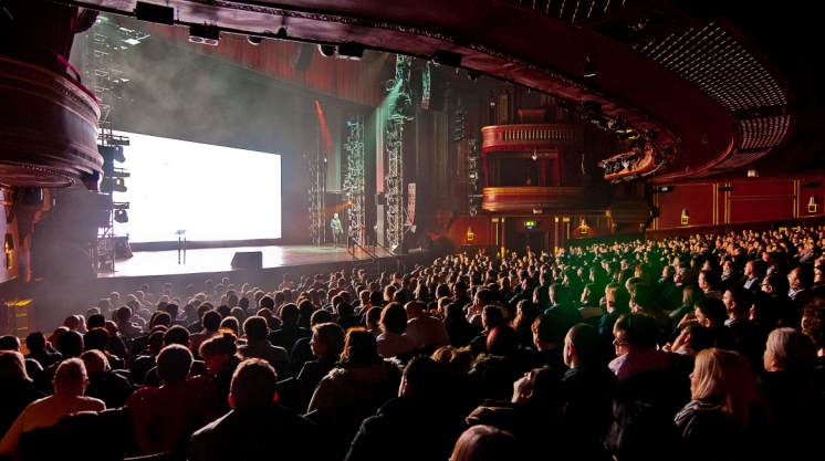 Packed auditorium at Dominion Theatre with advanced lighting for dynamic presentations.