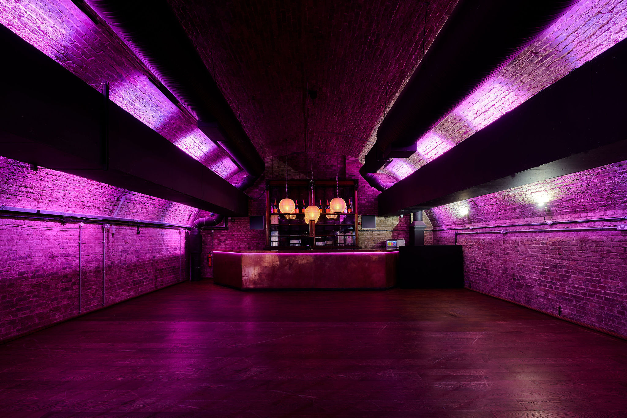 Modern event space with exposed brick and purple lighting for corporate or private gatherings.
