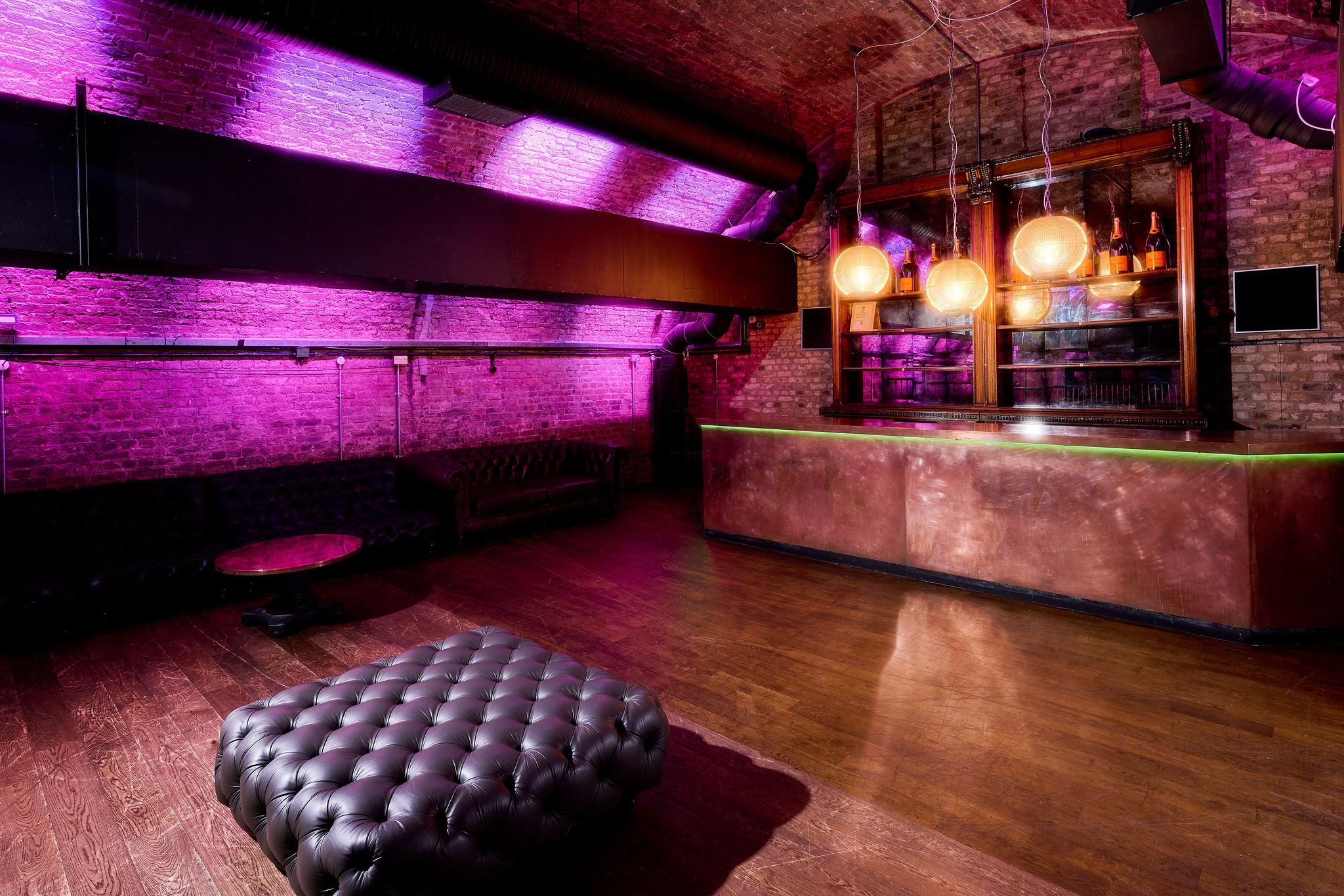 Stylish event space with exposed brick and purple lighting, perfect for cocktail receptions.
