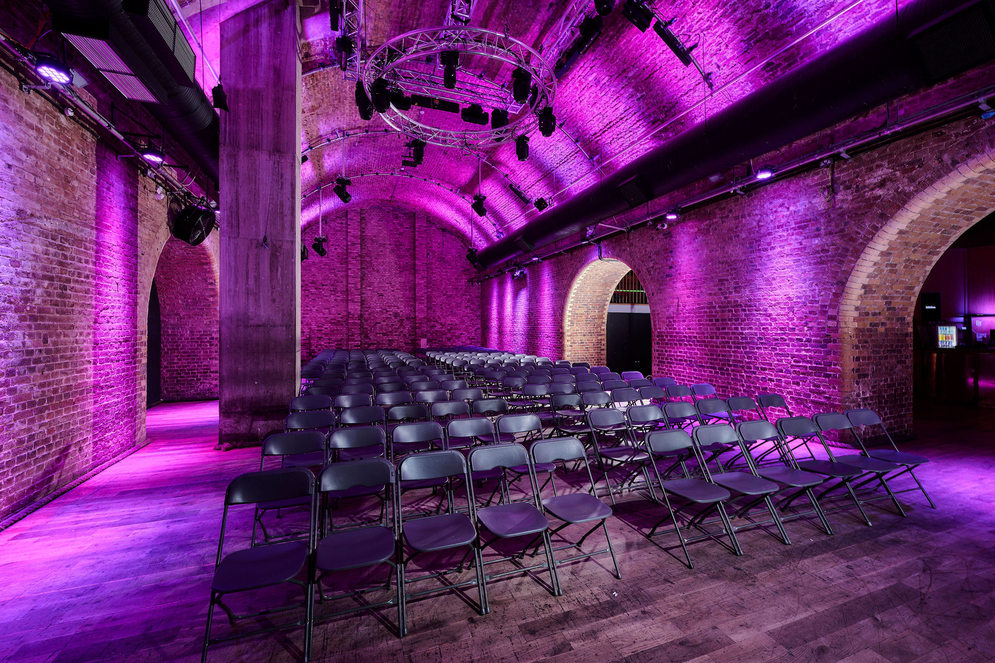 Versatile event space at The Steel Yard with exposed brick and purple lighting for seminars.