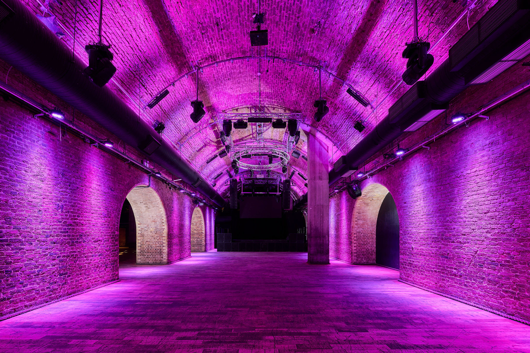 Spacious Steel Yard venue with exposed brick and purple lighting for events and gatherings.