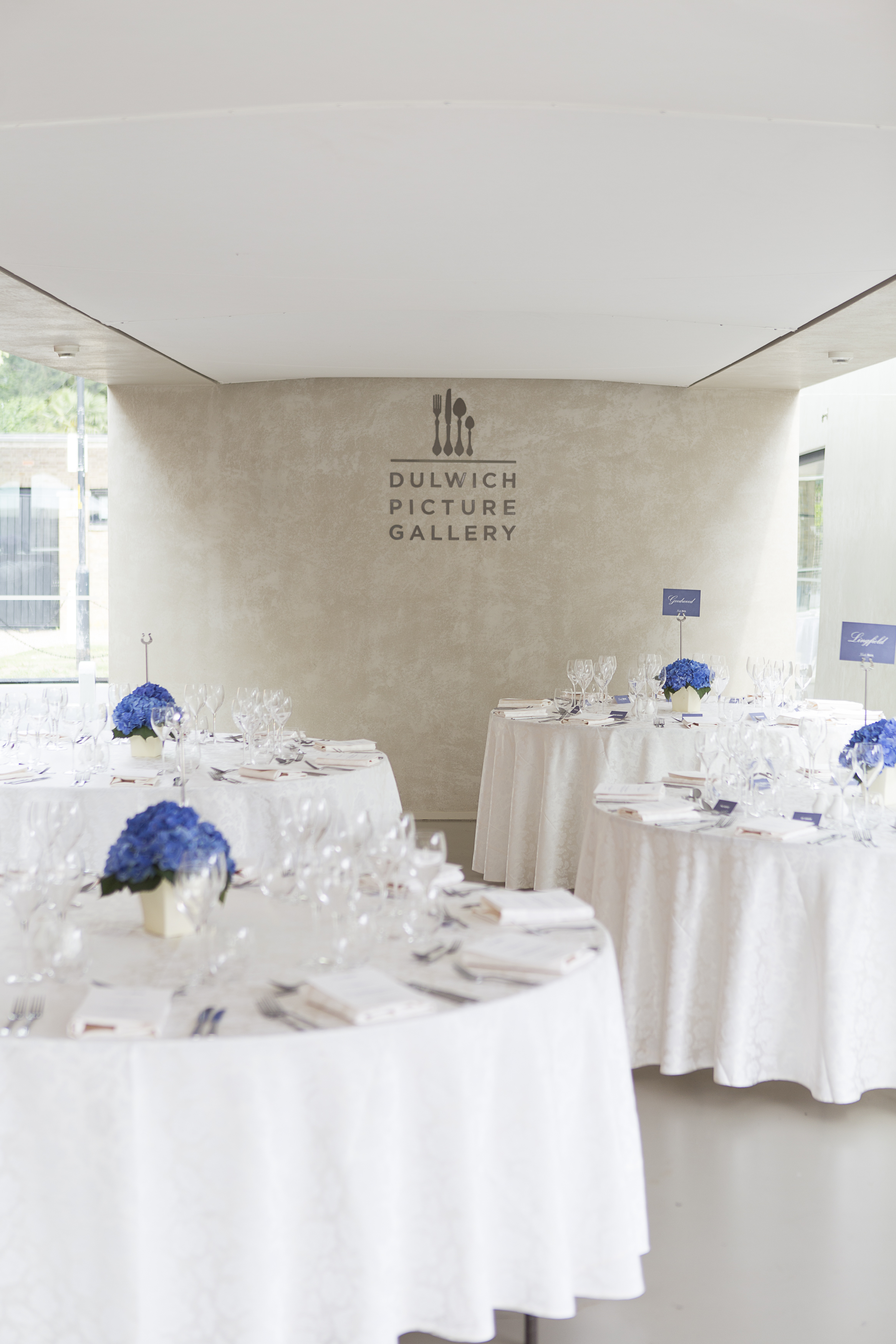 Elegant event space at Dulwich Picture Gallery with blue floral centerpieces.