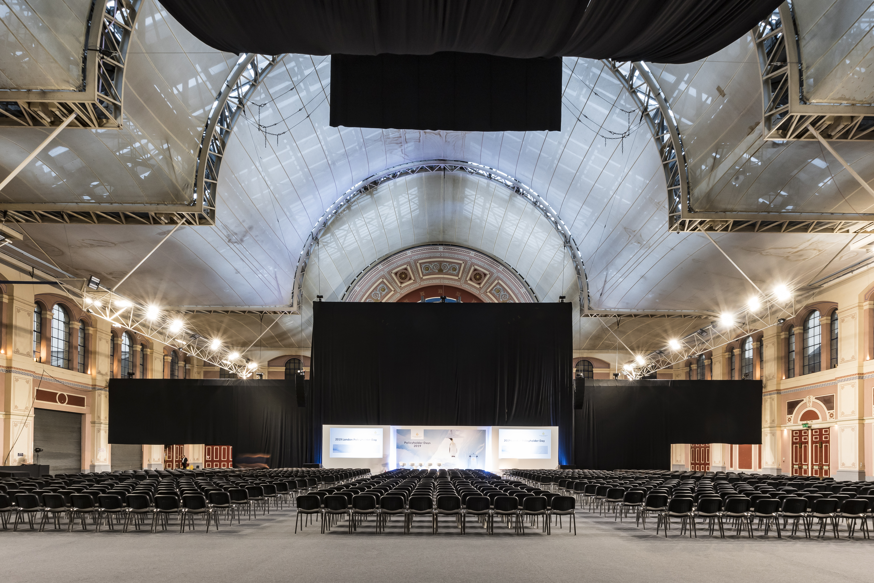 Great Hall at Alexandra Palace set for a conference with rows of black chairs.