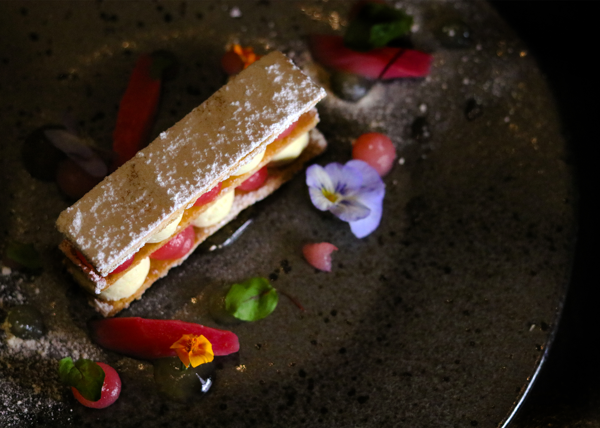 Elegant dessert with pastry layers and edible flowers at Opus Restaurant event.