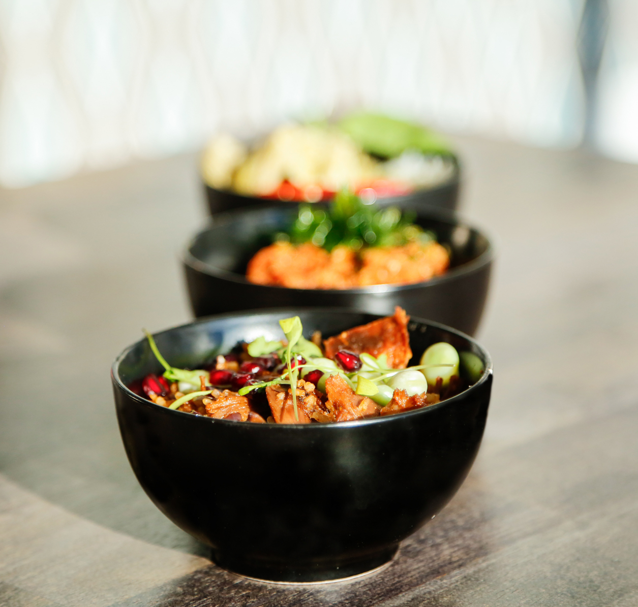 Vibrant dishes in black bowls at Bar Opus, perfect for event catering and networking.