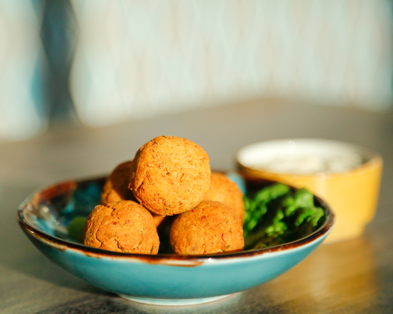 Golden-brown falafel balls with dipping sauce at Bar Opus for events and networking.