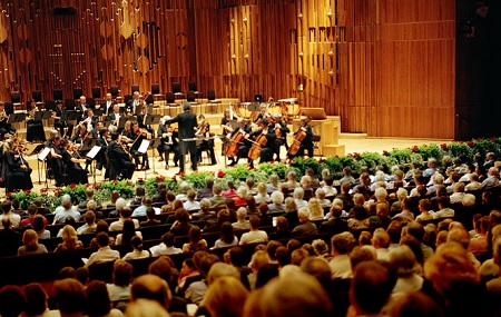 Orchestral performance at Barbican Hall with warm wood tones and lush greenery.