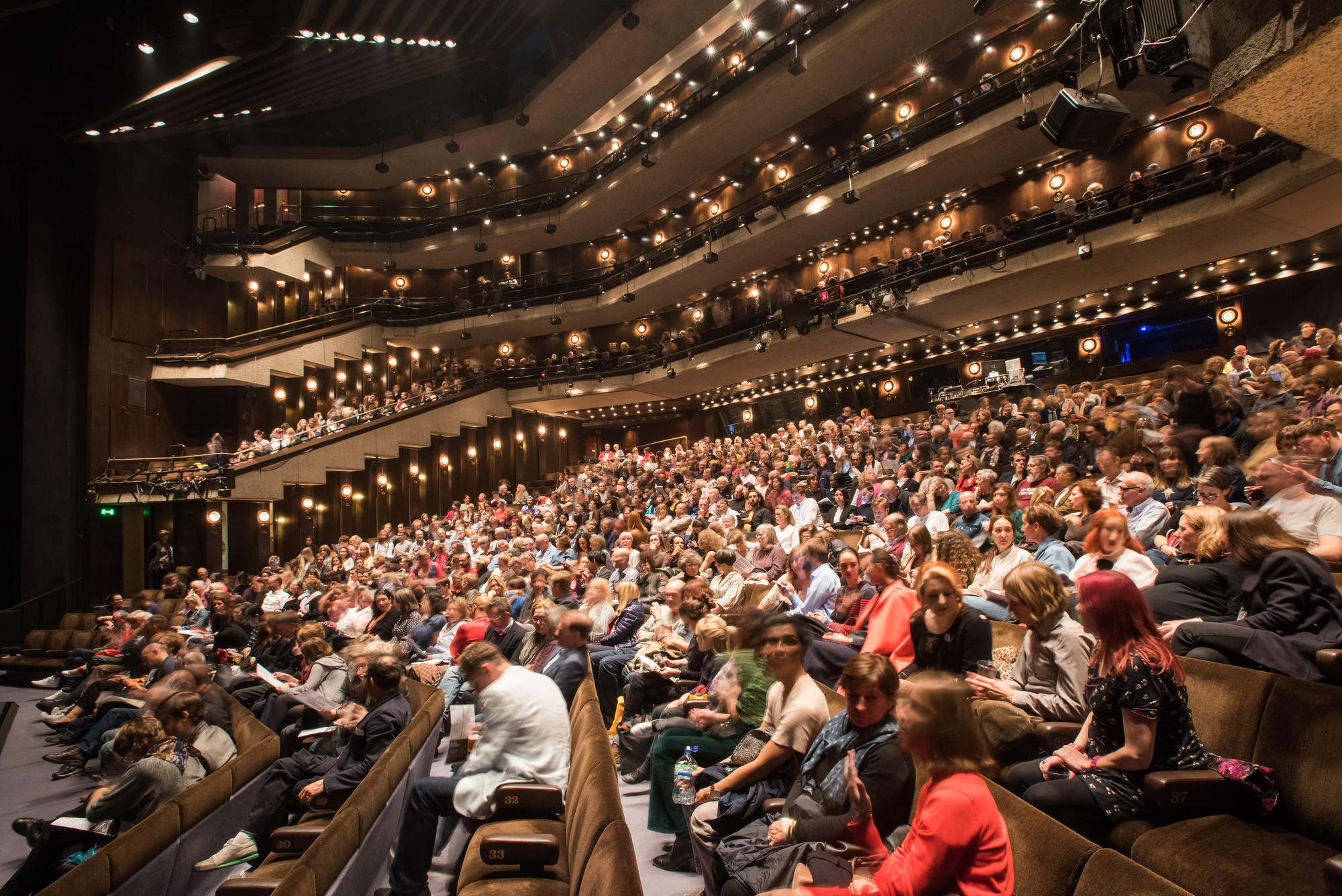 Packed Barbican Theatre auditorium with tiered seating for successful events and performances.