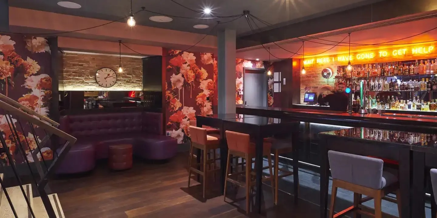 Stylish bar at Chez Mal London with floral wallpaper, ideal for networking events.