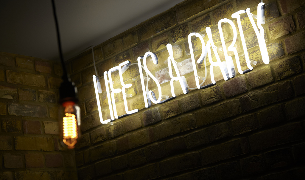 Vibrant neon "LIFE IS A PARTY" sign at Chez Mal, perfect for social gatherings and celebrations.