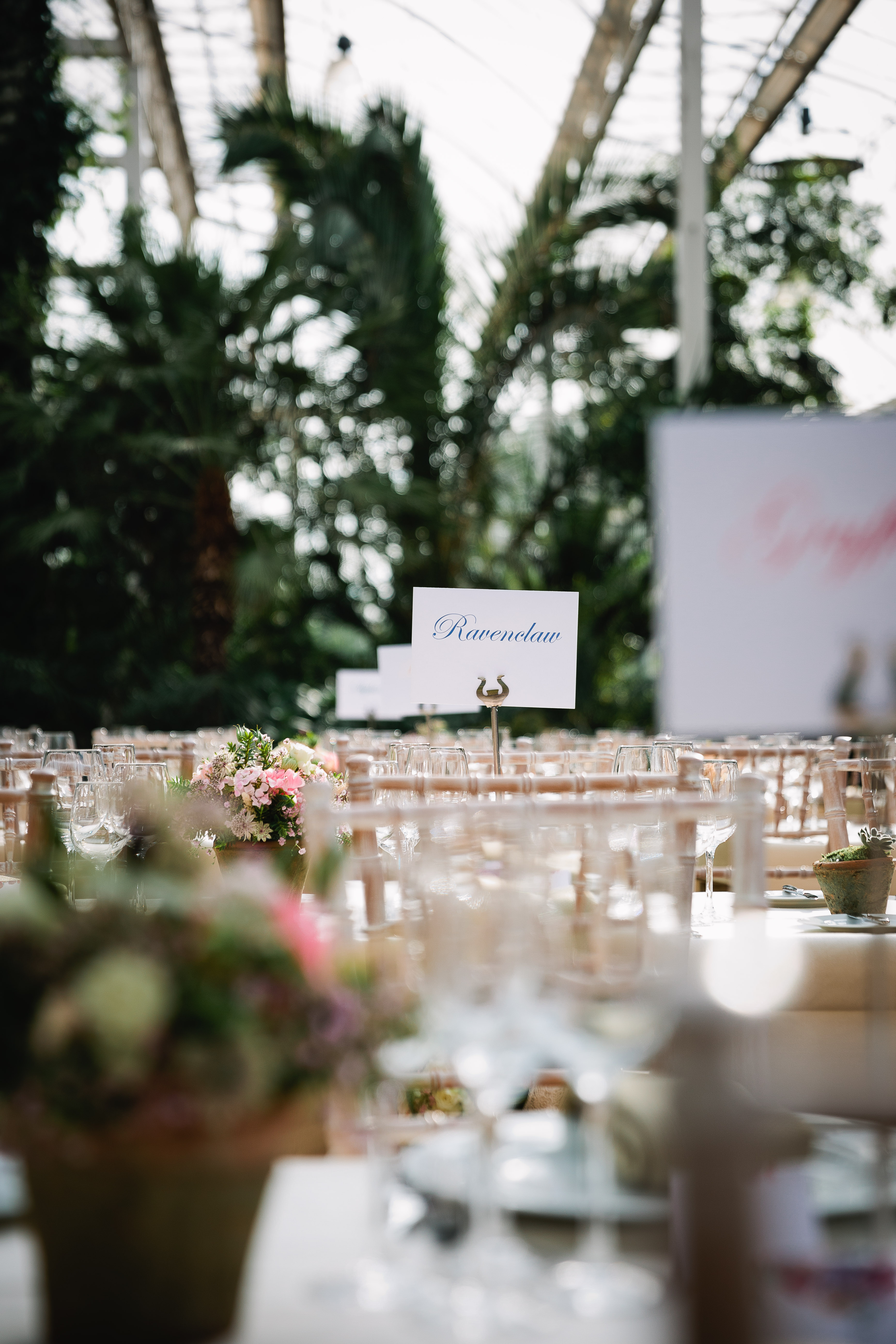 Elegant event space in Glasshouse, RHS Garden Wisley with floral centerpieces and greenery.
