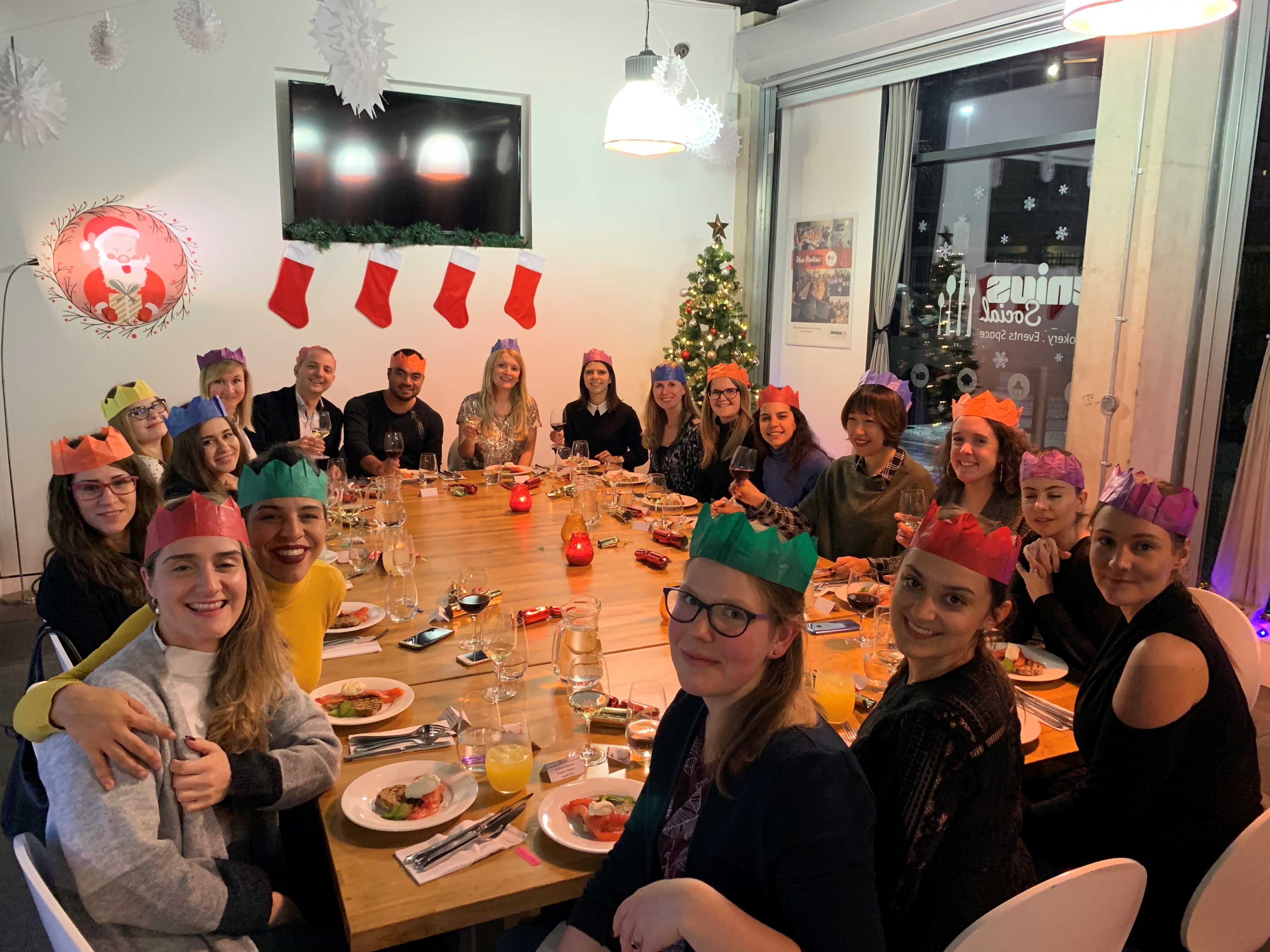Christmas cooking event with festive table and joyful participants in paper crowns.