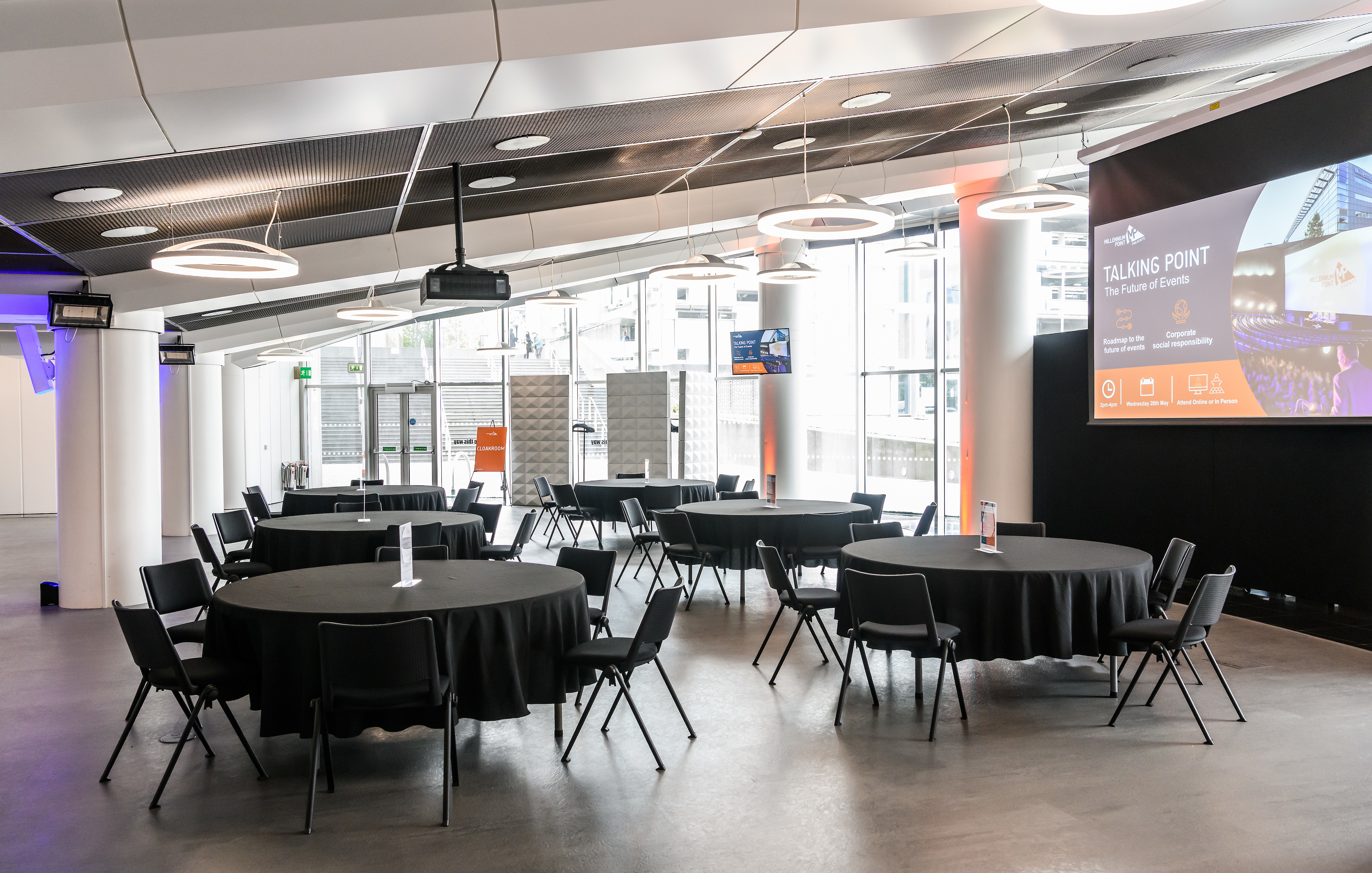 Versatile event space at Millennium Point with round tables for meetings and presentations.