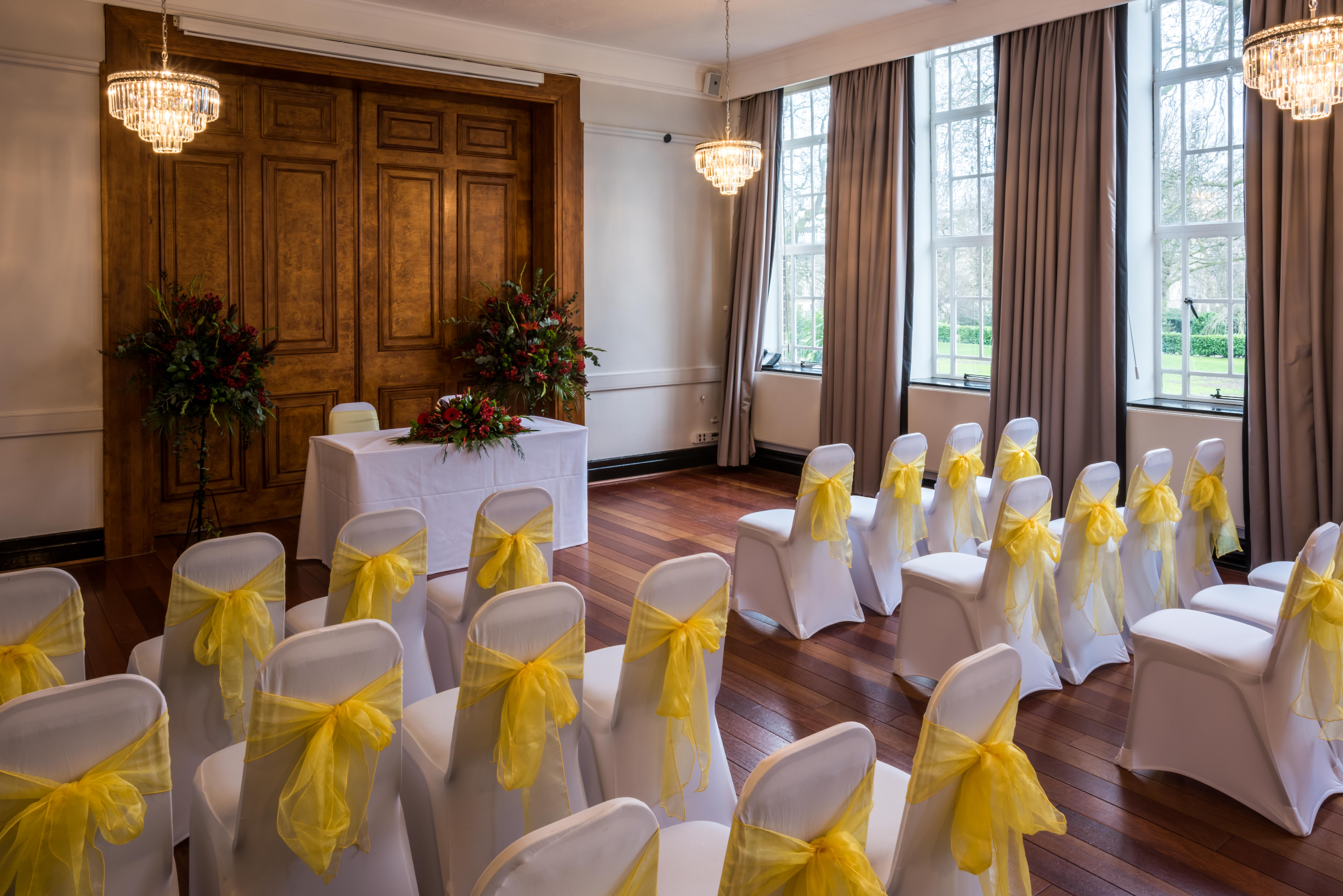 Tuke Common Room with white chairs and yellow sashes, perfect for weddings and corporate events.