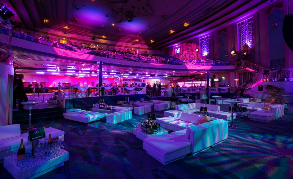 "Elegant Christmas party at Troxy with plush seating and vibrant purple lighting."