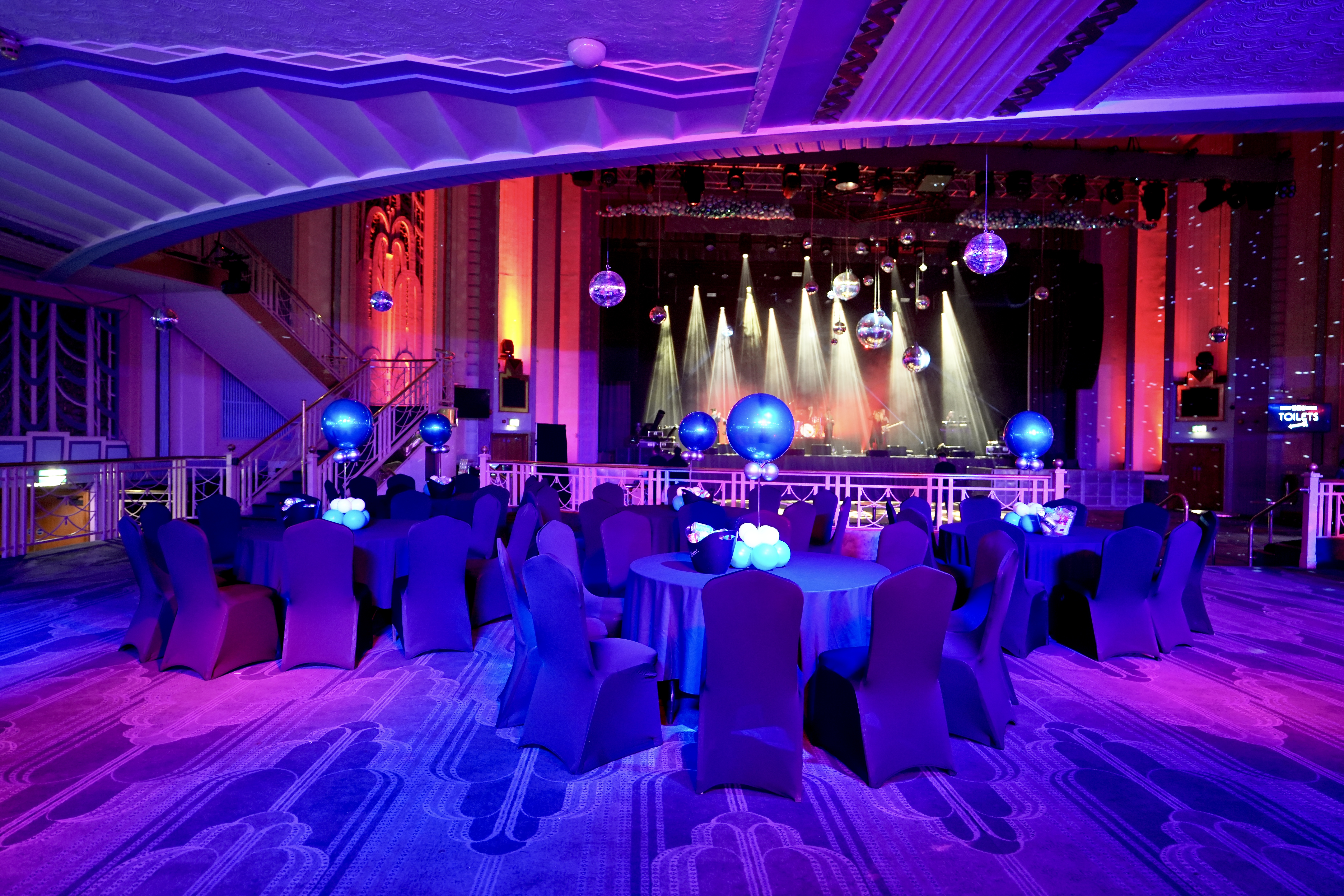 Christmas party gala at Troxy with elegant blue tables and dynamic stage lighting.