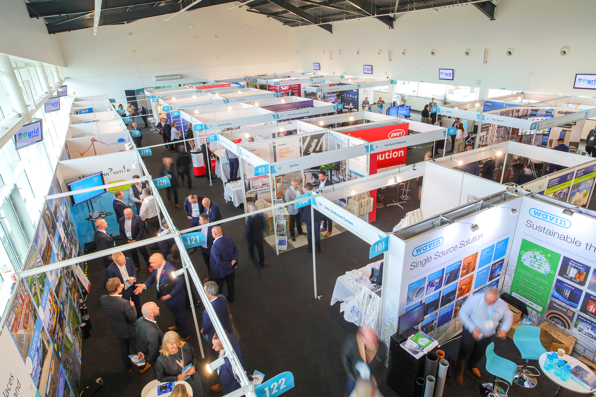 Bustling Silverstone exhibition hall with booths and attendees networking at a conference.