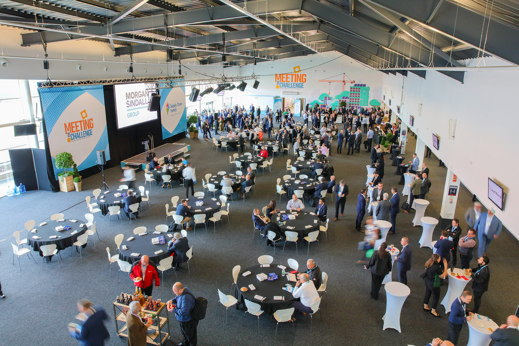 Spacious Silverstone conference hall with attendees networking at round tables.