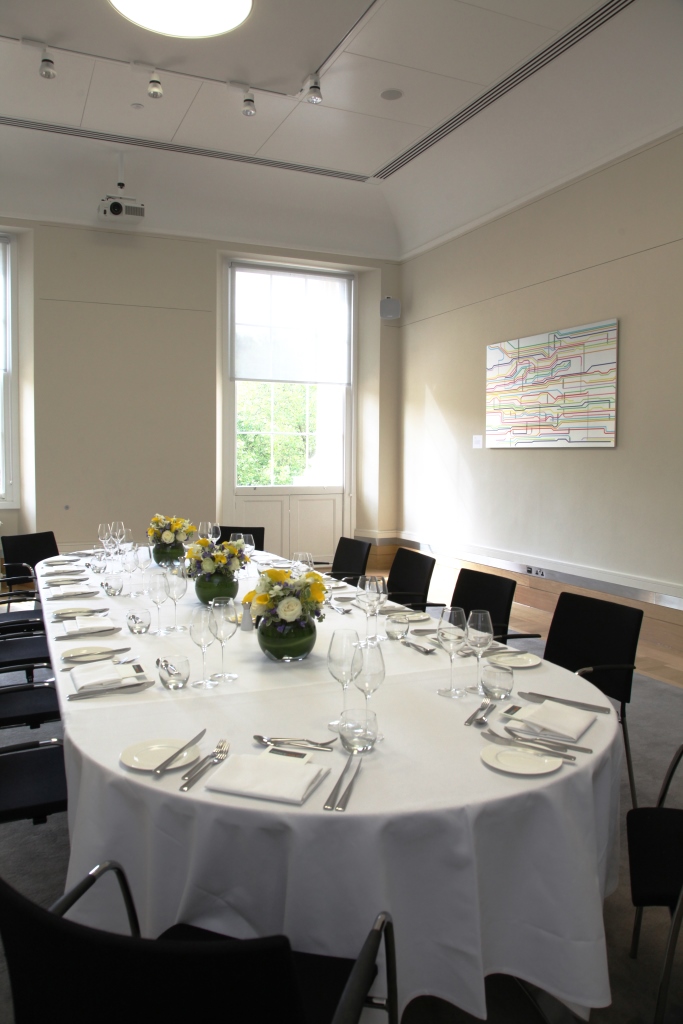Elegant meeting space with long table and floral centerpieces for corporate events.