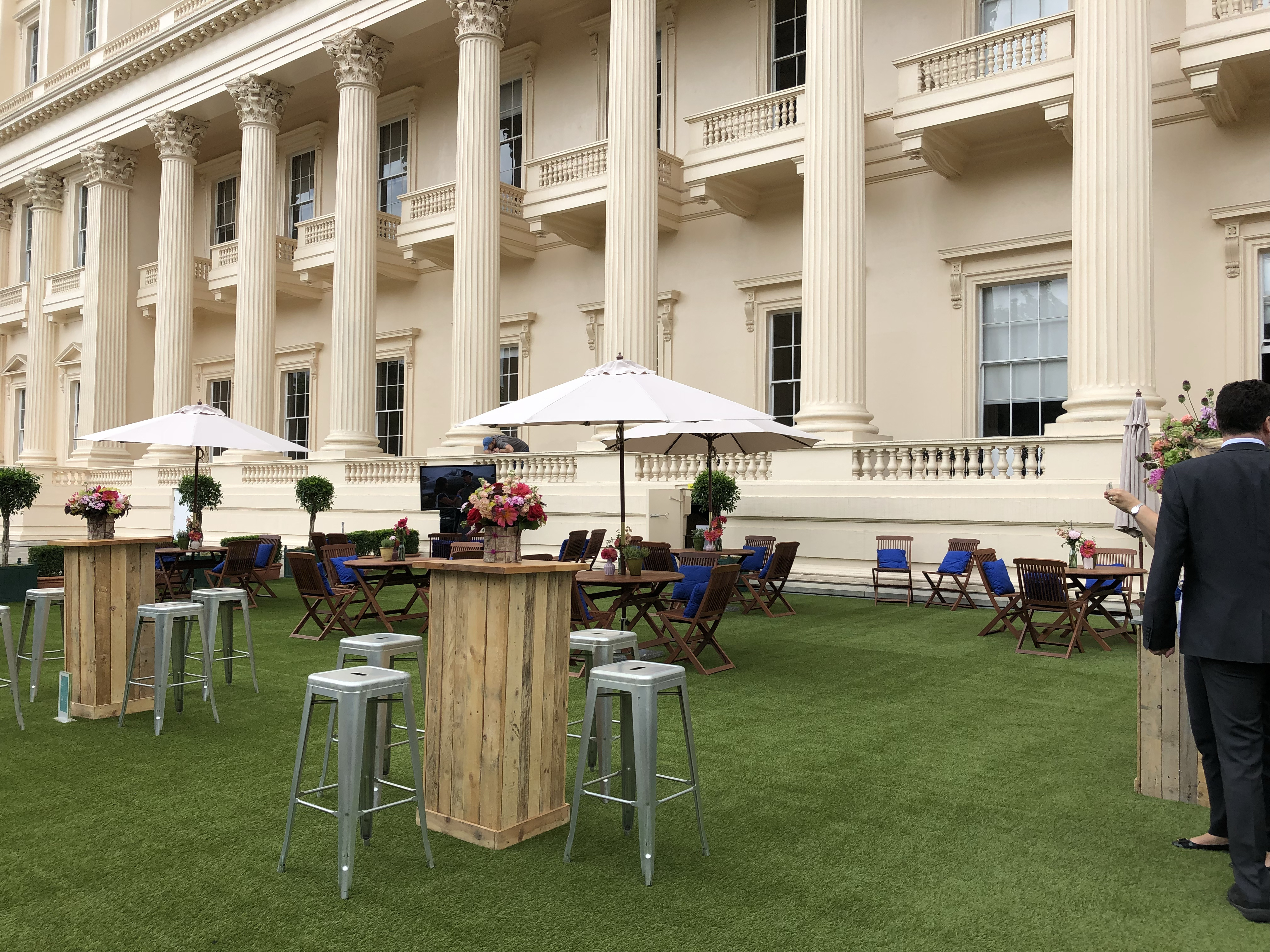 Elegant outdoor event space with wooden bar tables at Prince Philip House.