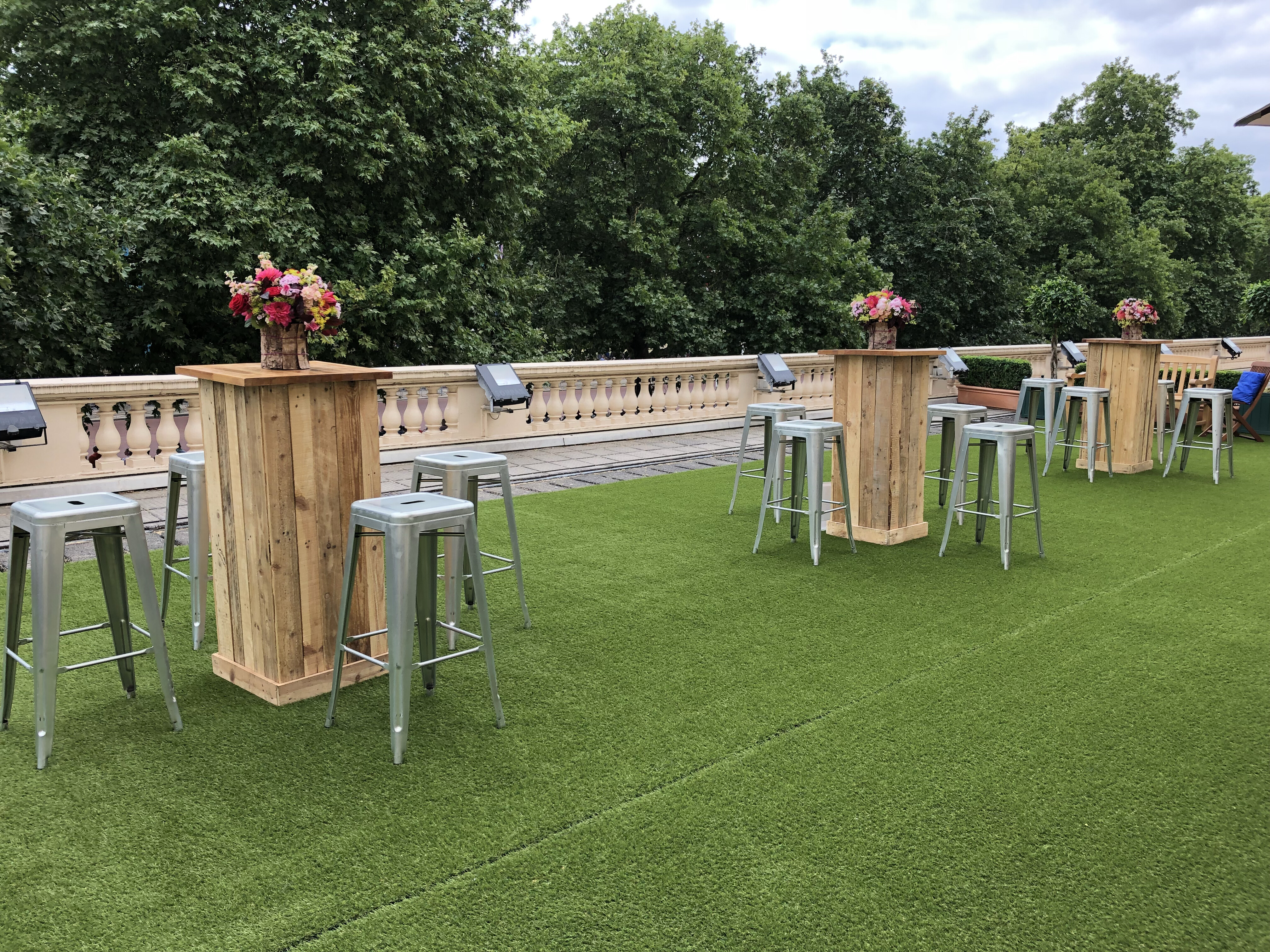 Stylish outdoor event space with floral centerpieces for cocktail receptions.