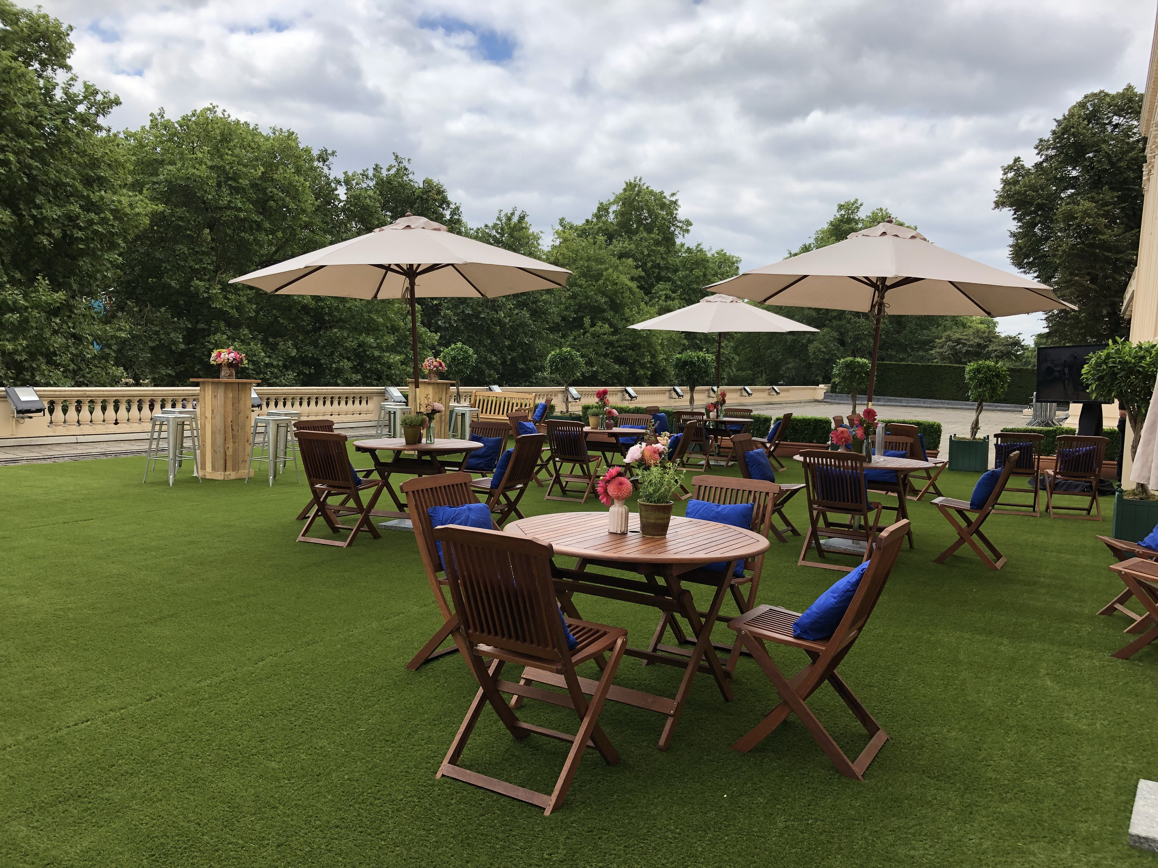 Outdoor event space at Prince Philip House with wooden tables and lush greenery.