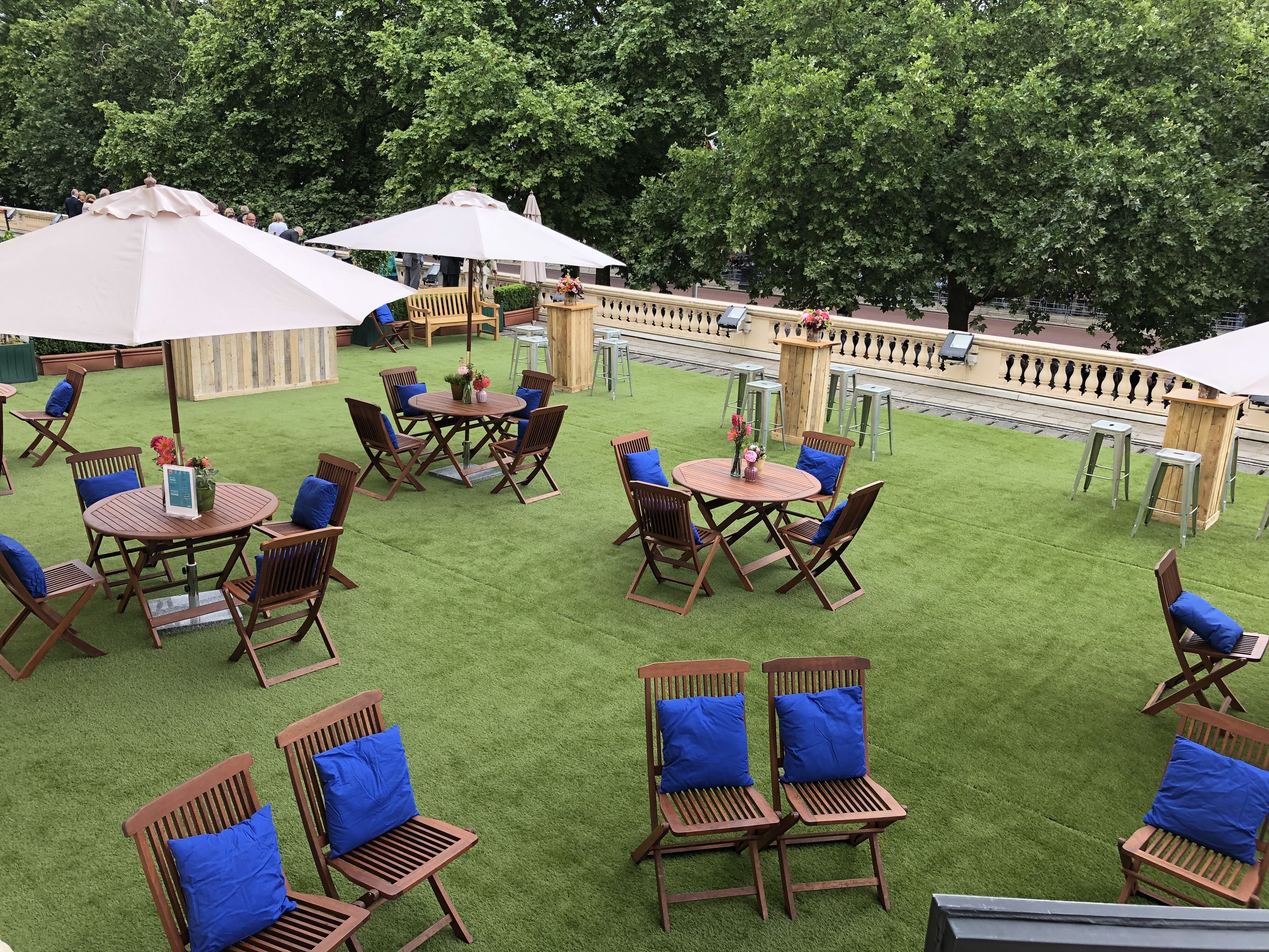 Outdoor event space at Prince Philip House with wooden tables and blue cushions.