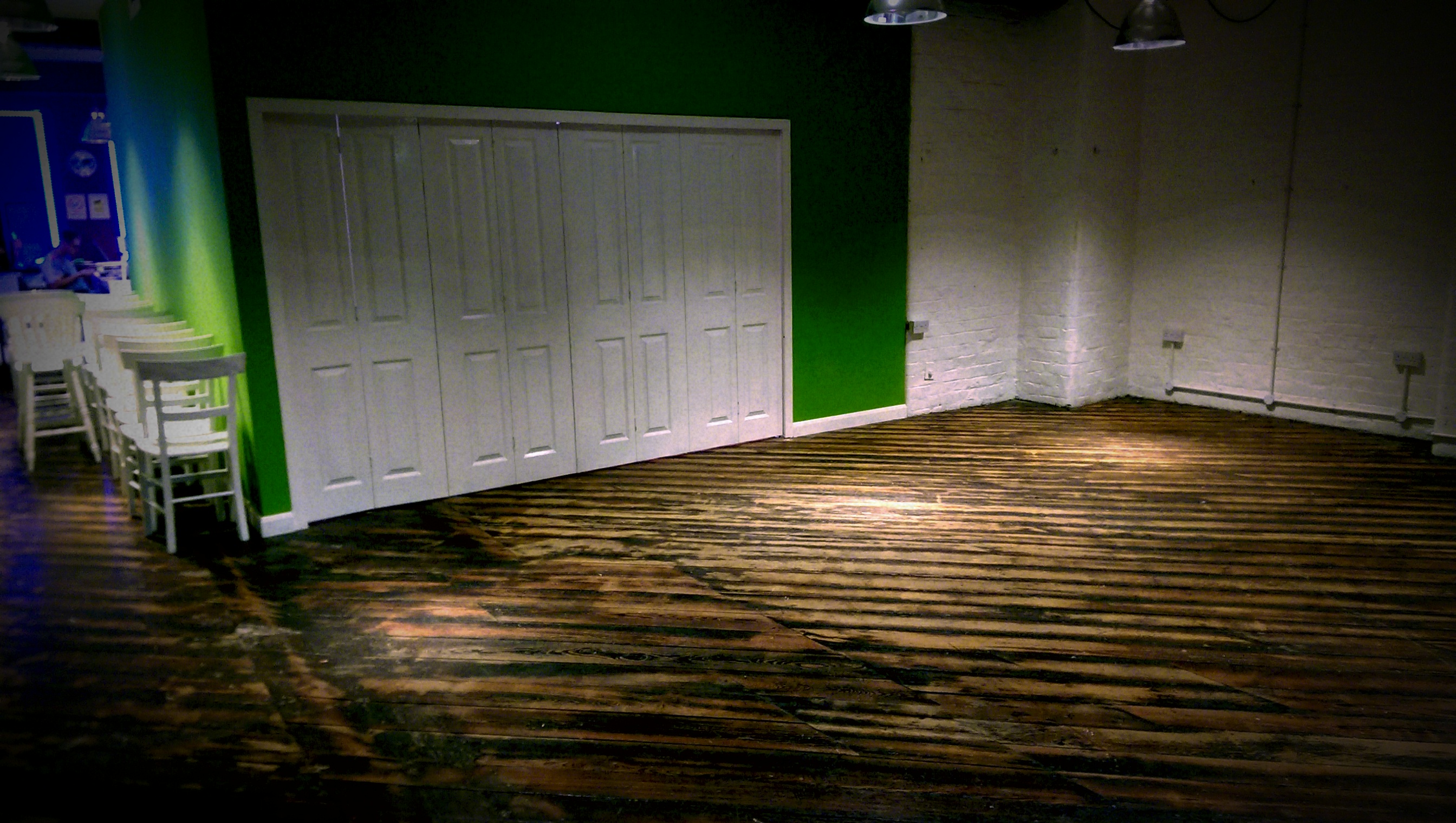 Versatile event space with green accent wall, ideal for workshops and networking events.