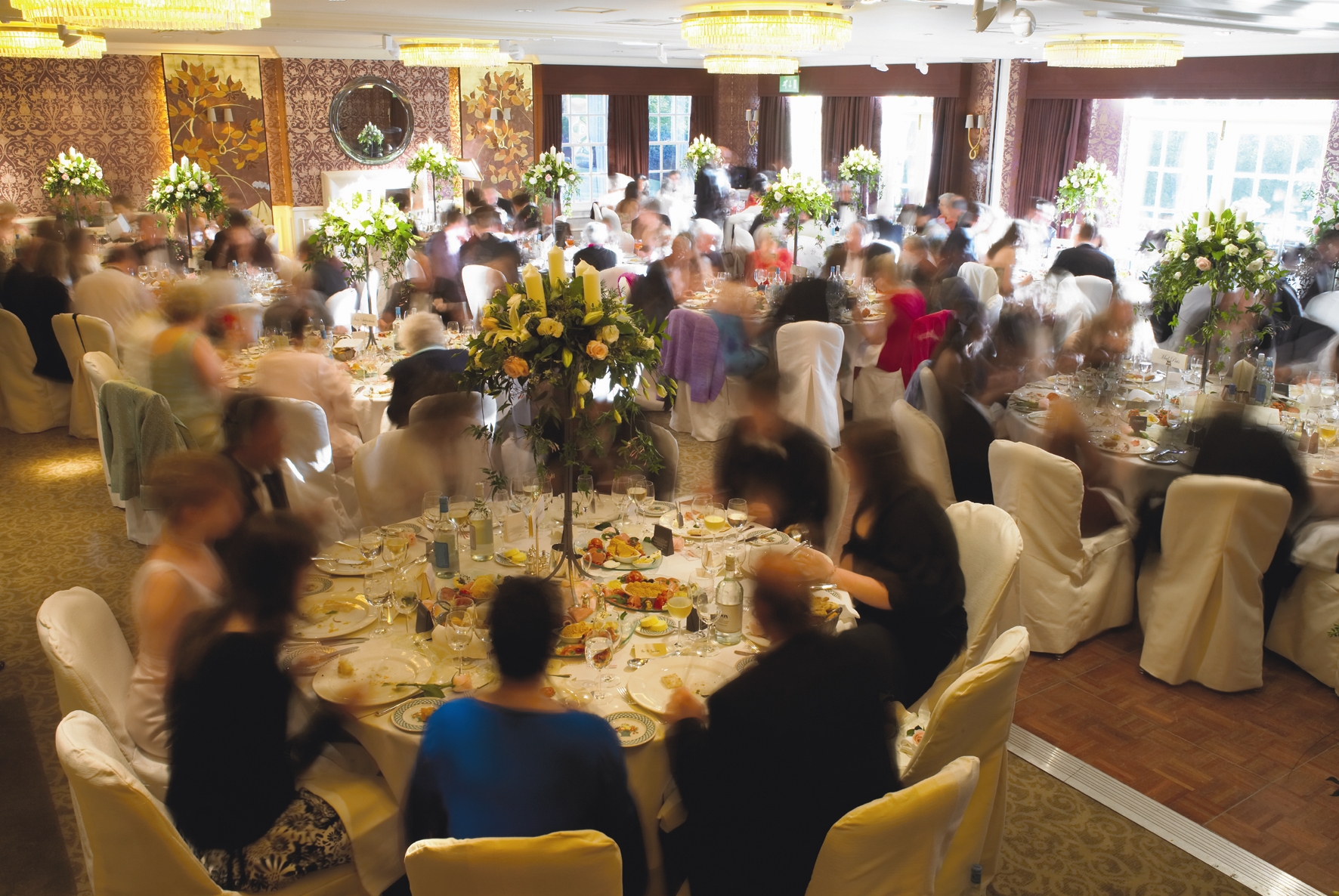 Elegant banquet at Chewton Glen Hotel with floral centerpieces and lively guests.