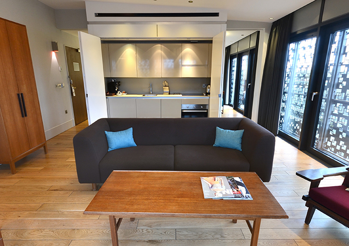 Modern meeting space with sofa and kitchenette at Town Hall Hotel for brainstorming sessions.
